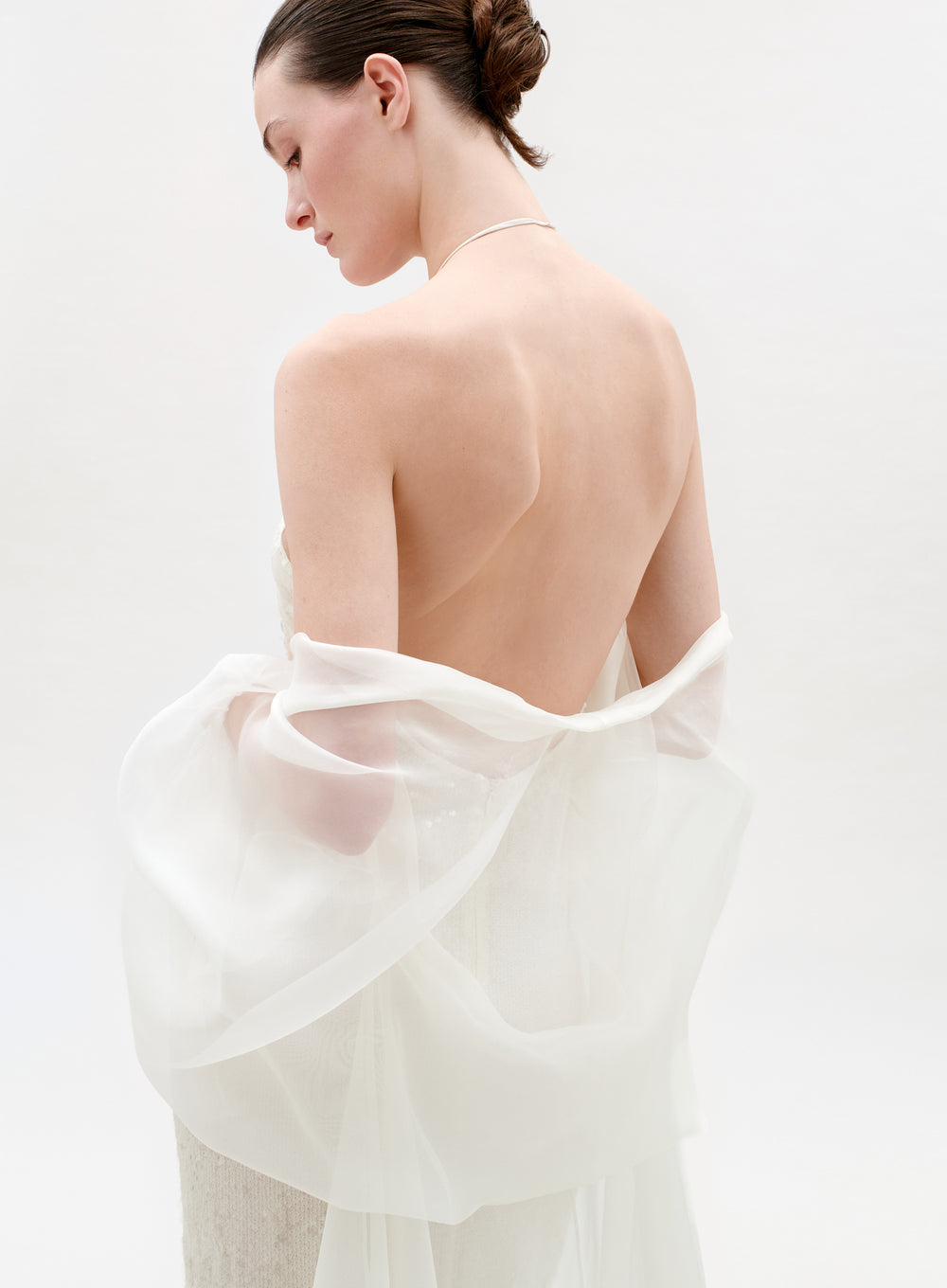 Woman wearing a sheer white garment against a light background