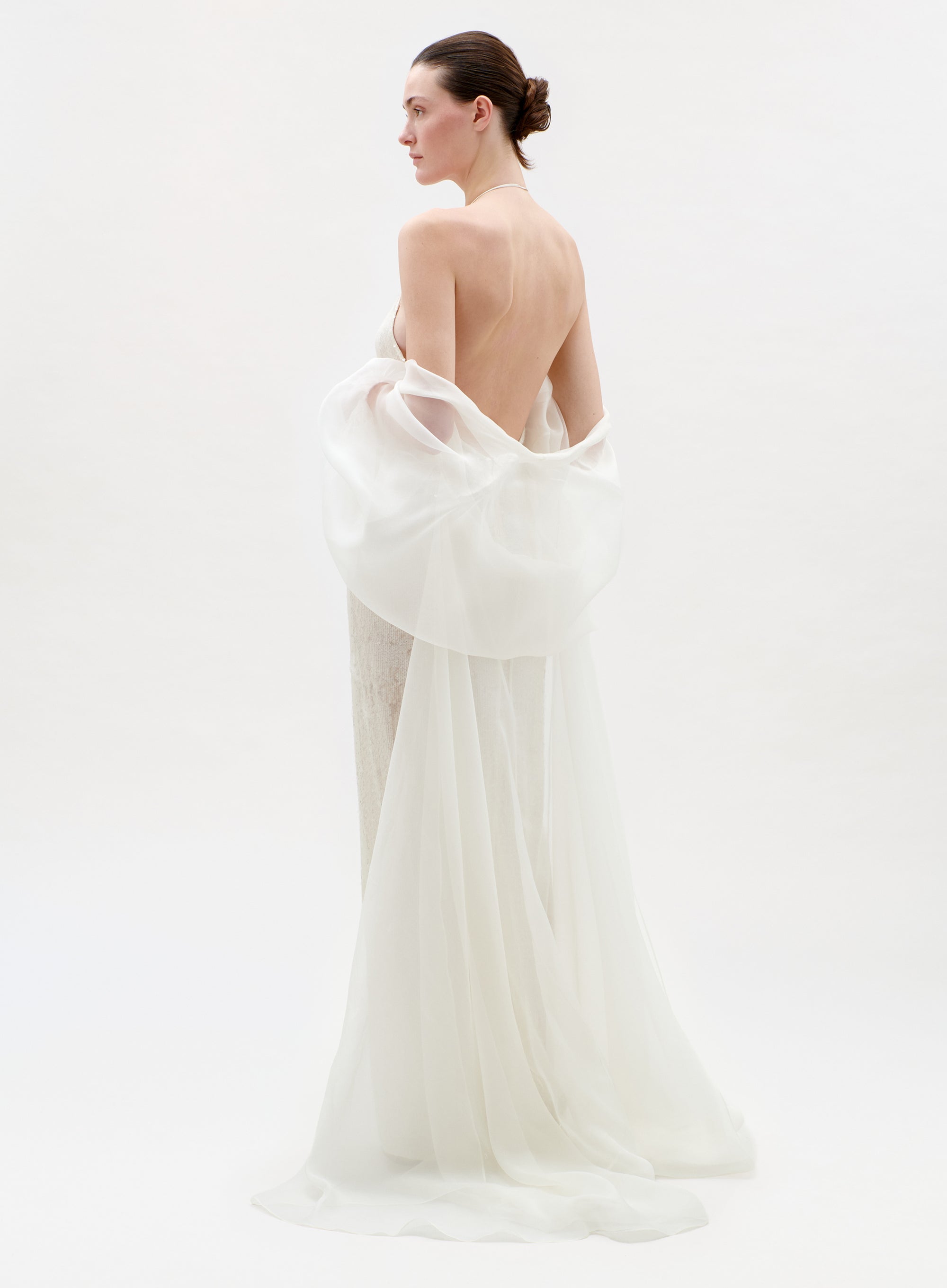 Woman wearing a white gown with a low back on a white background