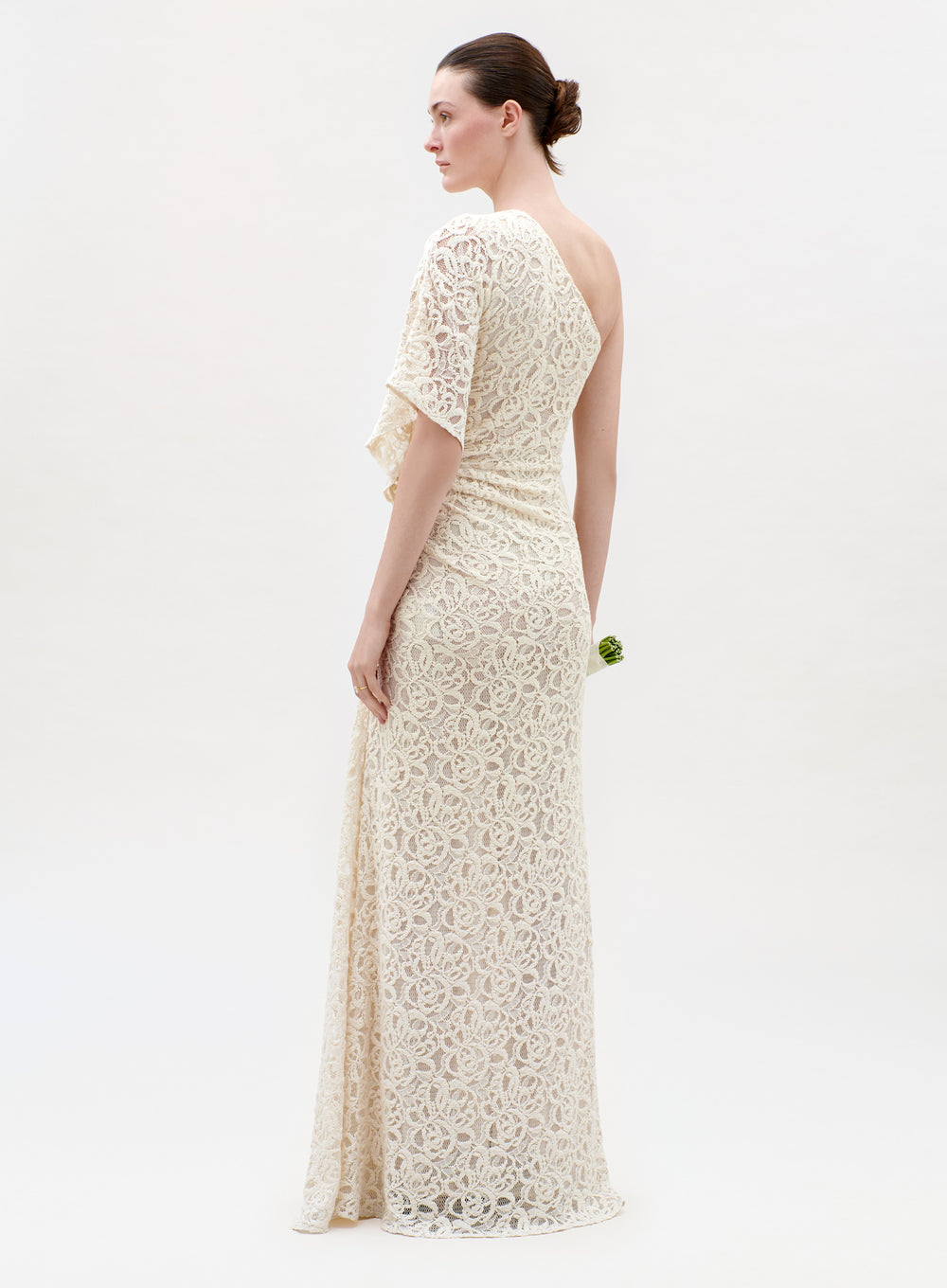 Woman wearing a long, off-white lace dress on a white background