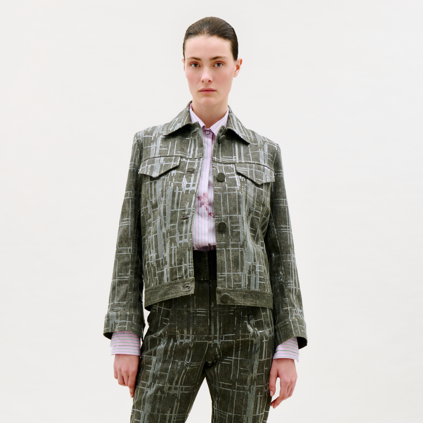 Person wearing a patterned jacket and pants on a white background