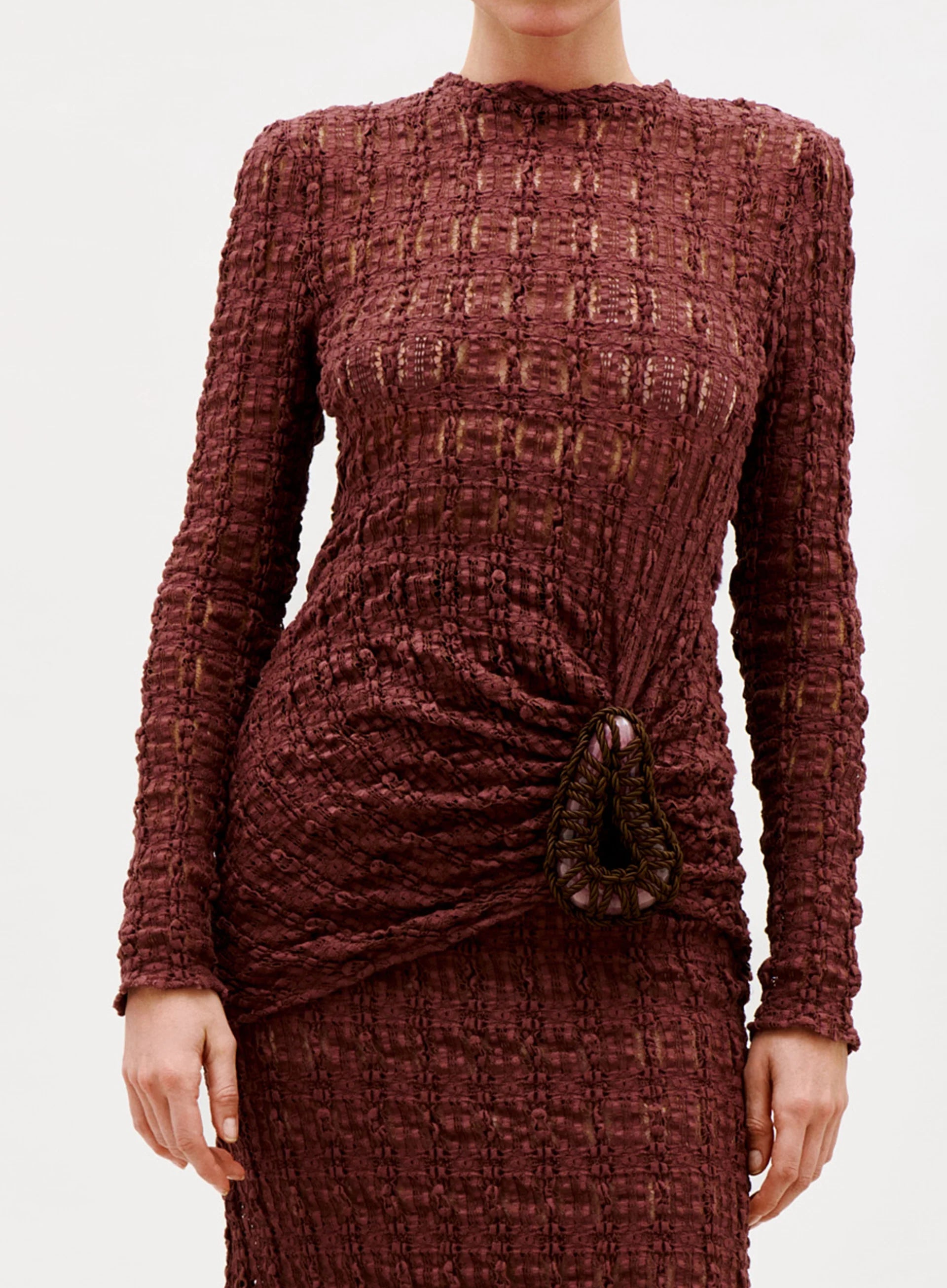 A person wearing the Roma T-Shirt, crafted from luxurious Italian fabric with a textured finish and long sleeves, featuring a gathered detail and a decorative brooch at the waist. The background is plain white.