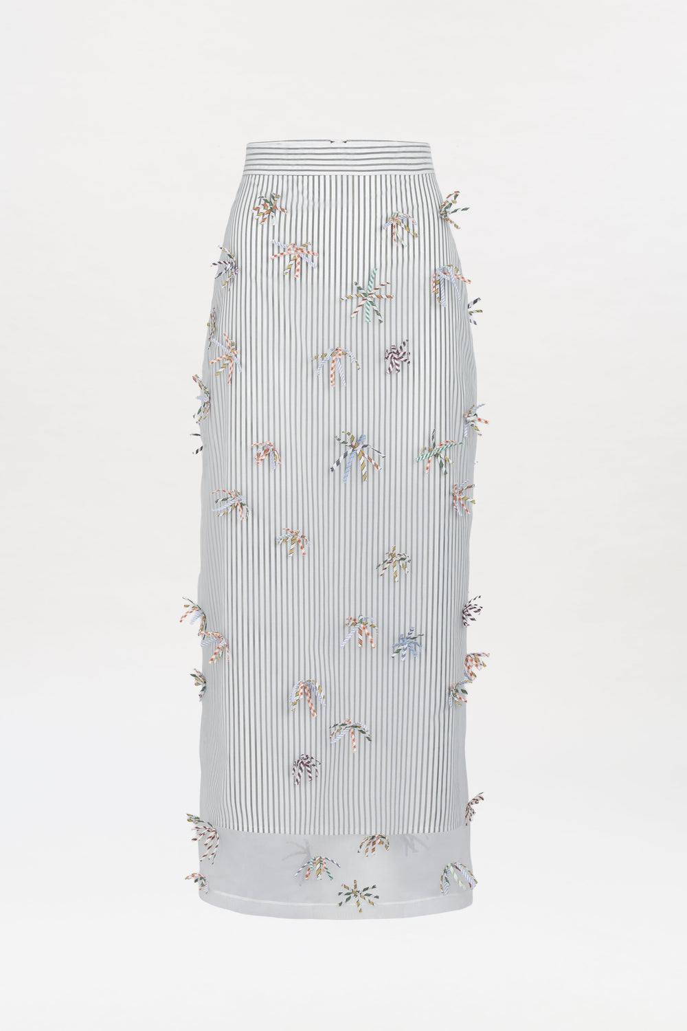 Uma Skirt: A long, high-waisted white skirt featuring thin vertical black stripes and colorful small 3D floral embellishments scattered across the fabric.