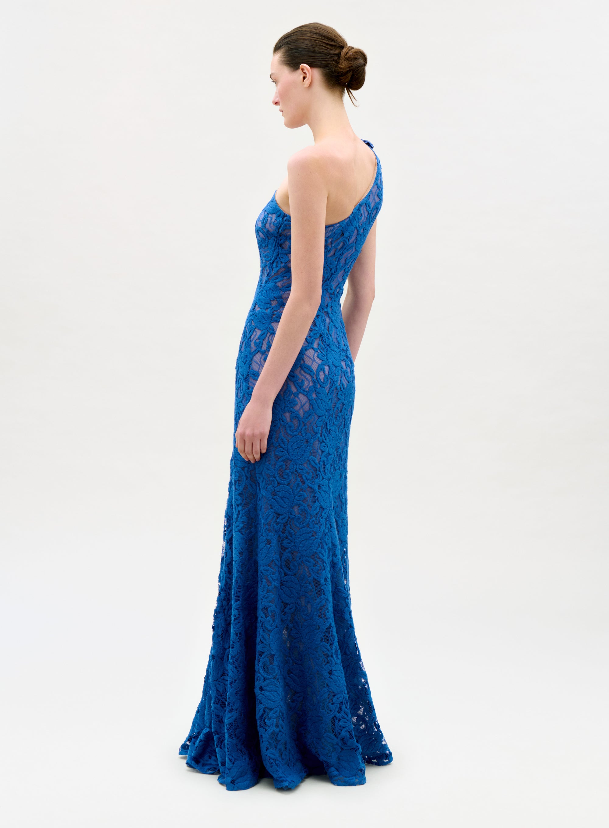Woman wearing a blue lace evening gown on a white background