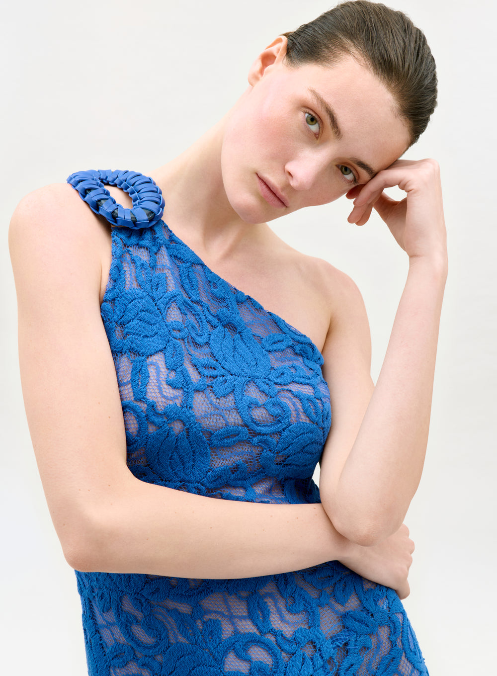 Woman wearing a blue lace dress against a white background