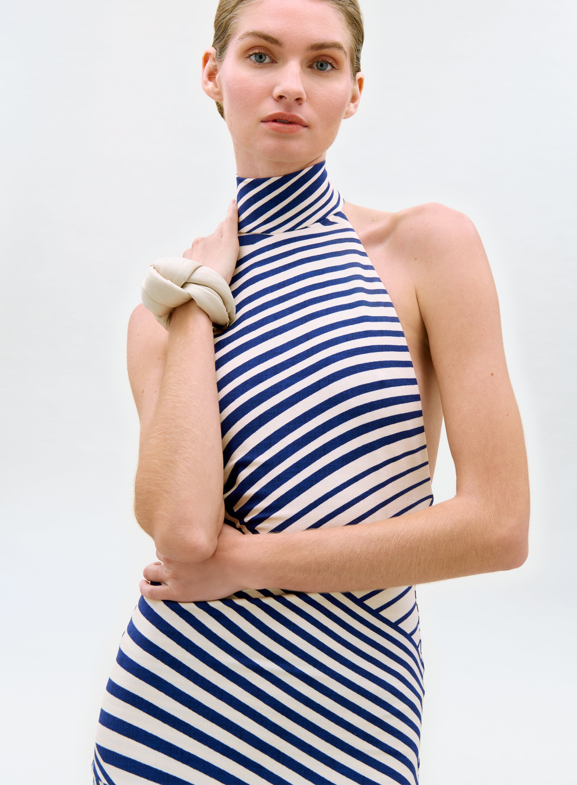 Woman wearing a blue and white striped dress against a plain background