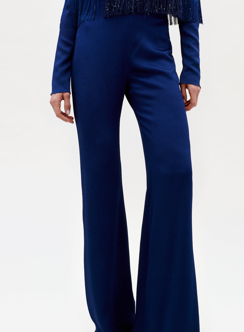 A person wears the Palermo Pant—high-waisted, wide-leg navy blue pants—with a matching long-sleeve fringed top, standing against a plain light background.