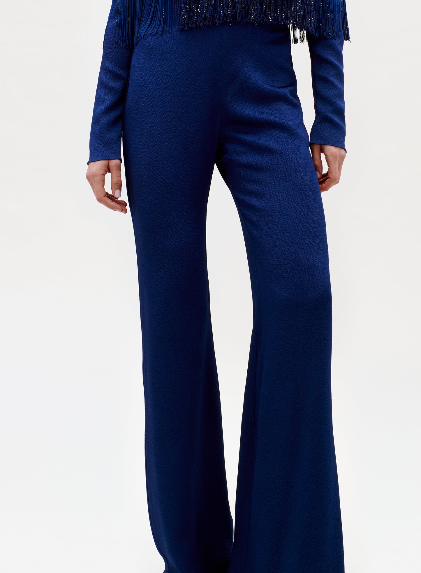 A person wears the Palermo Pant—high-waisted, wide-leg navy blue pants—with a matching long-sleeve fringed top, standing against a plain light background.