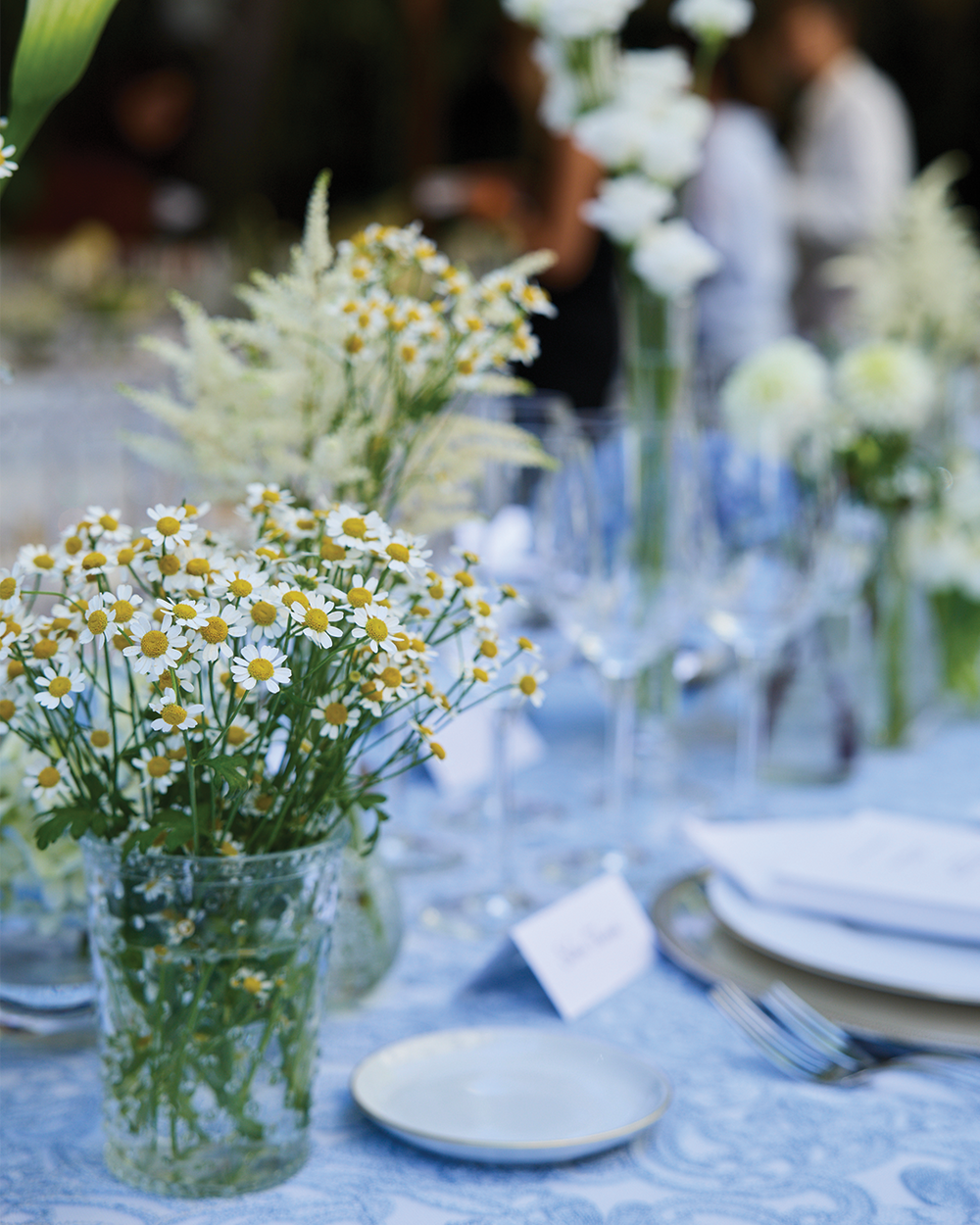 Table setting with floral arrangements and plates on a blue tablecloth.