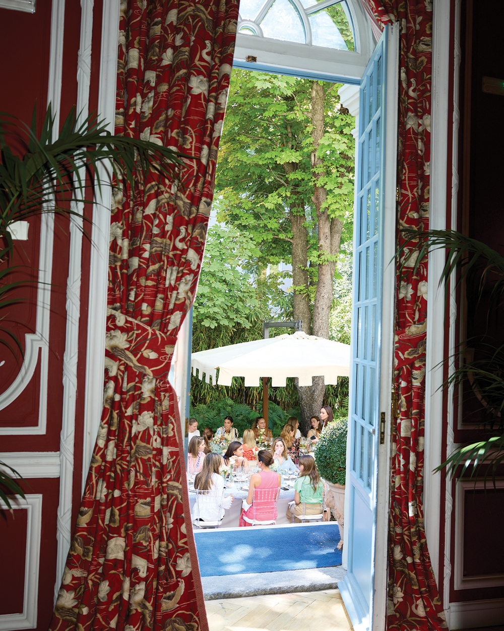 Indoor setting with red floral curtains and outdoor view of people dining.