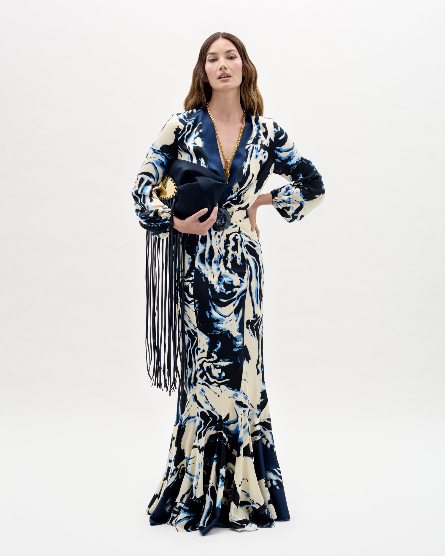 Woman wearing a long, patterned dress with fringes on a white background