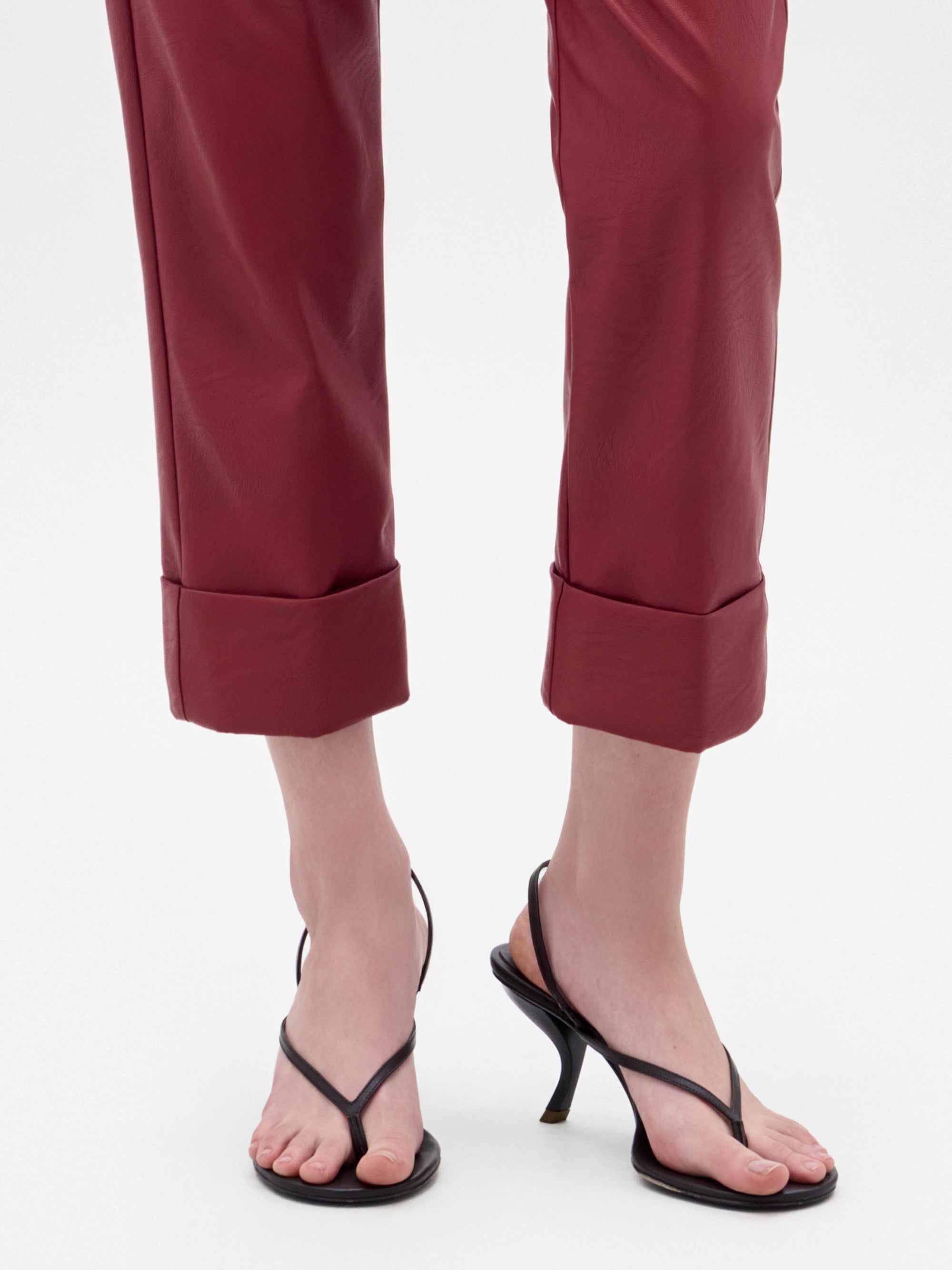 The Aurora Heels are black strappy sandals featuring a thin thong-style toe strap and a curved heel, showcased against a plain light background.