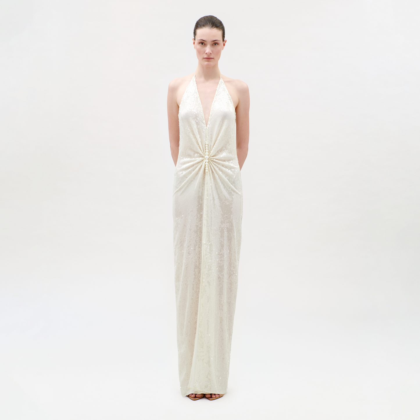 Woman wearing a white halter neck gown on a plain background