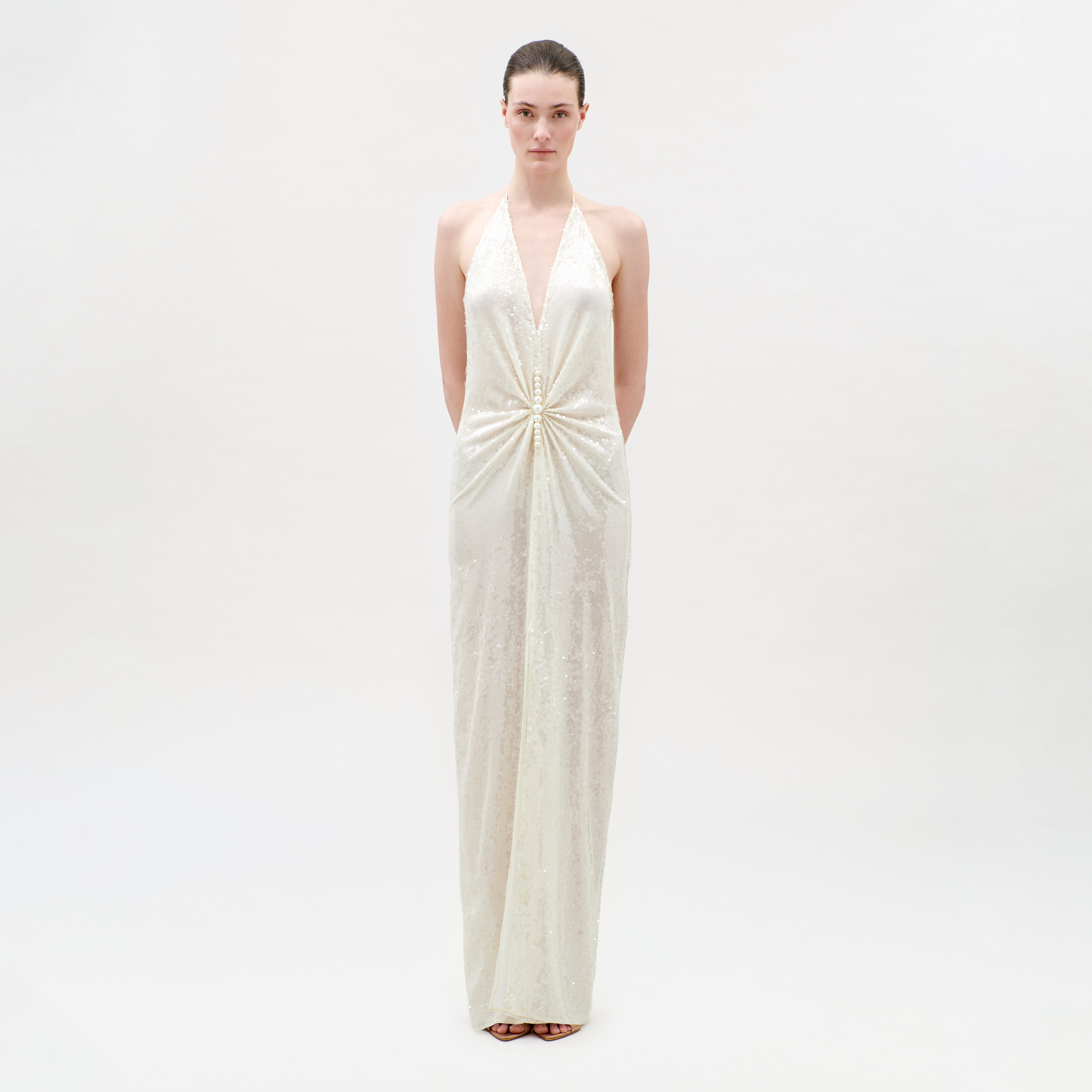 Woman wearing a white halter neck gown on a plain background