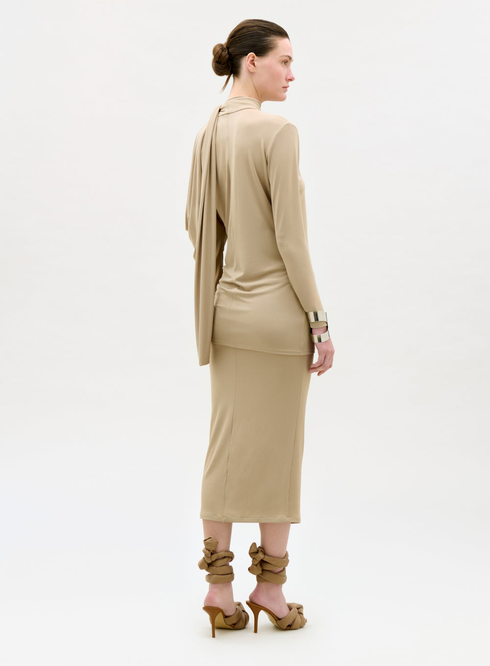 Woman wearing a beige dress with a matching jacket on a white background
