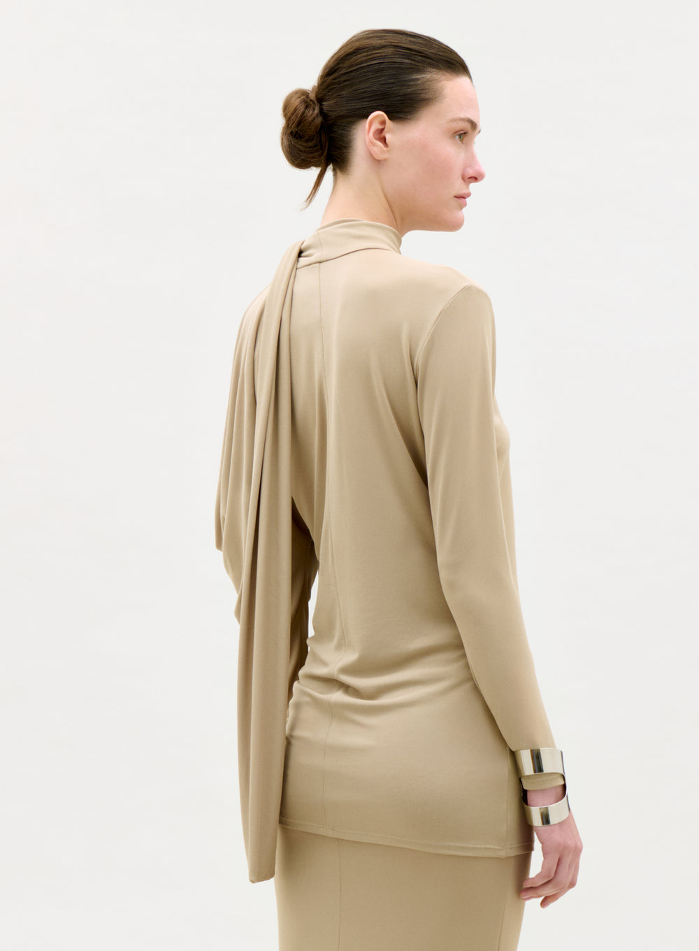 Woman wearing a beige outfit with a matching jacket on a white background