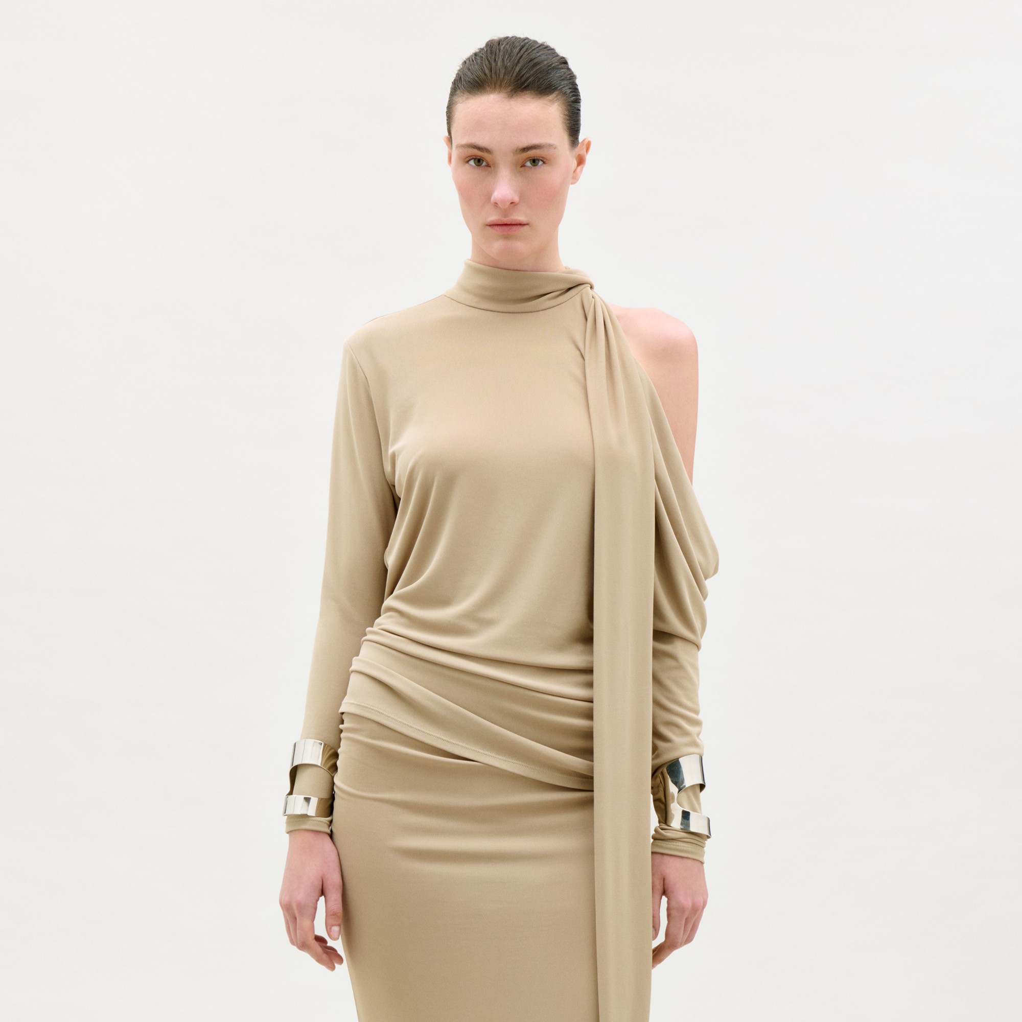 Woman wearing a beige dress with a draped design on a white background