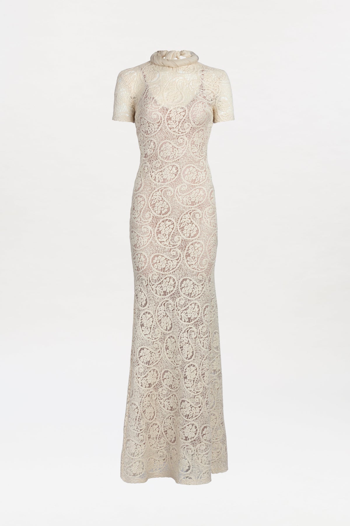 Tini Dress: An elegant, long cream lace dress featuring short sleeves, a high sheer neckline, and a fitted silhouette, displayed on a white background.