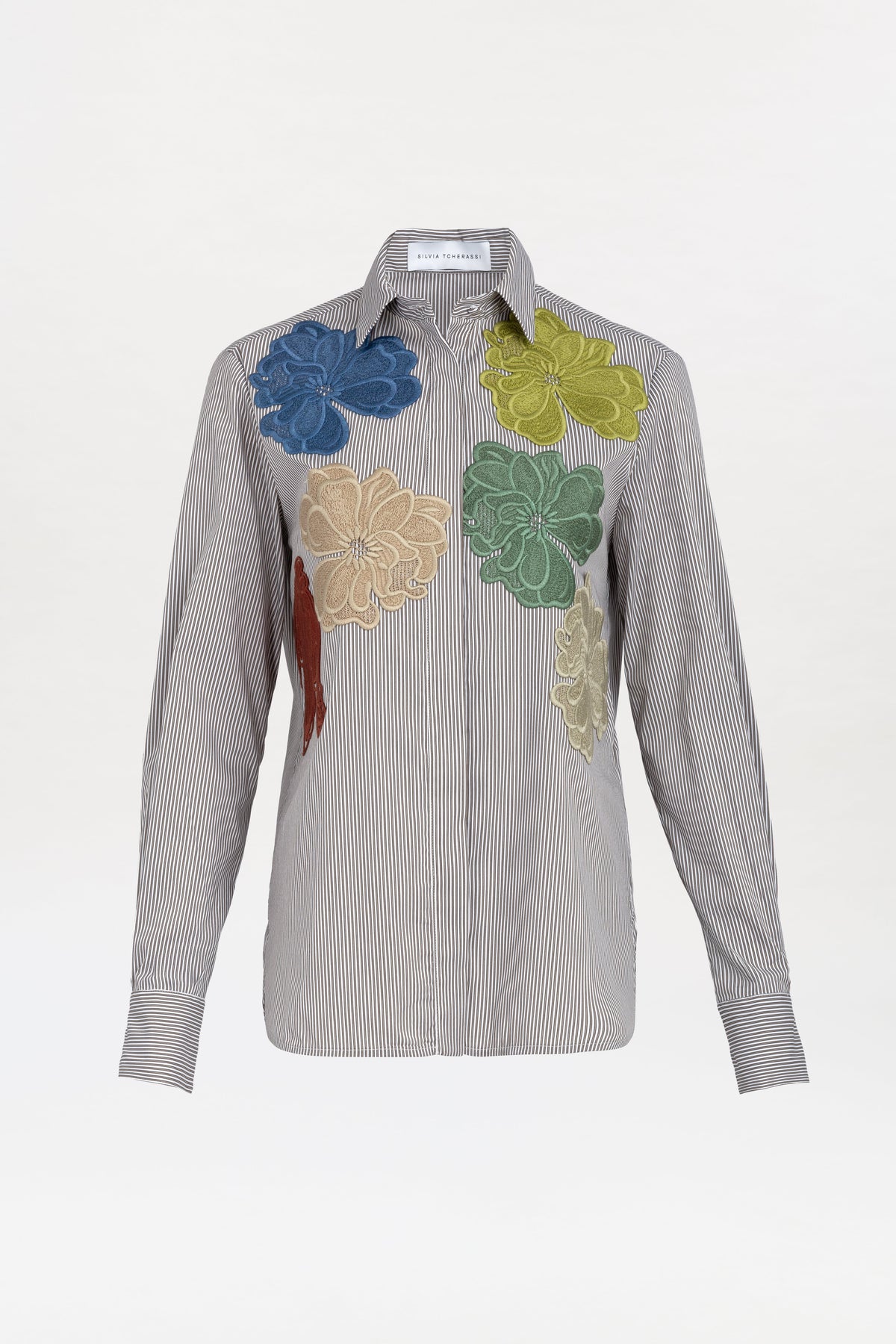 The Warda Shirt is a long-sleeve, black-and-white striped button-up featuring large colorful floral appliqués in blue, yellow, green, beige, and red across the upper front.