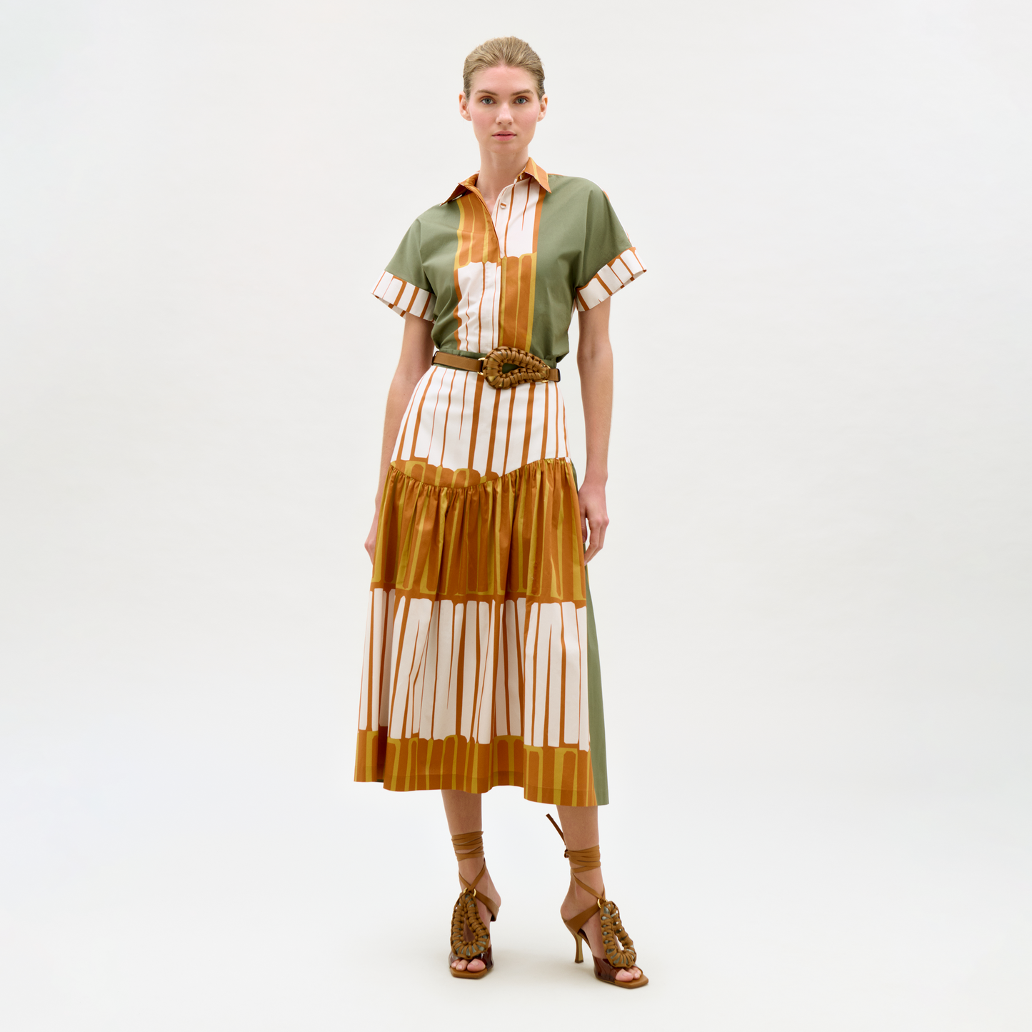 Woman wearing a green and brown striped dress with a belt on a white background