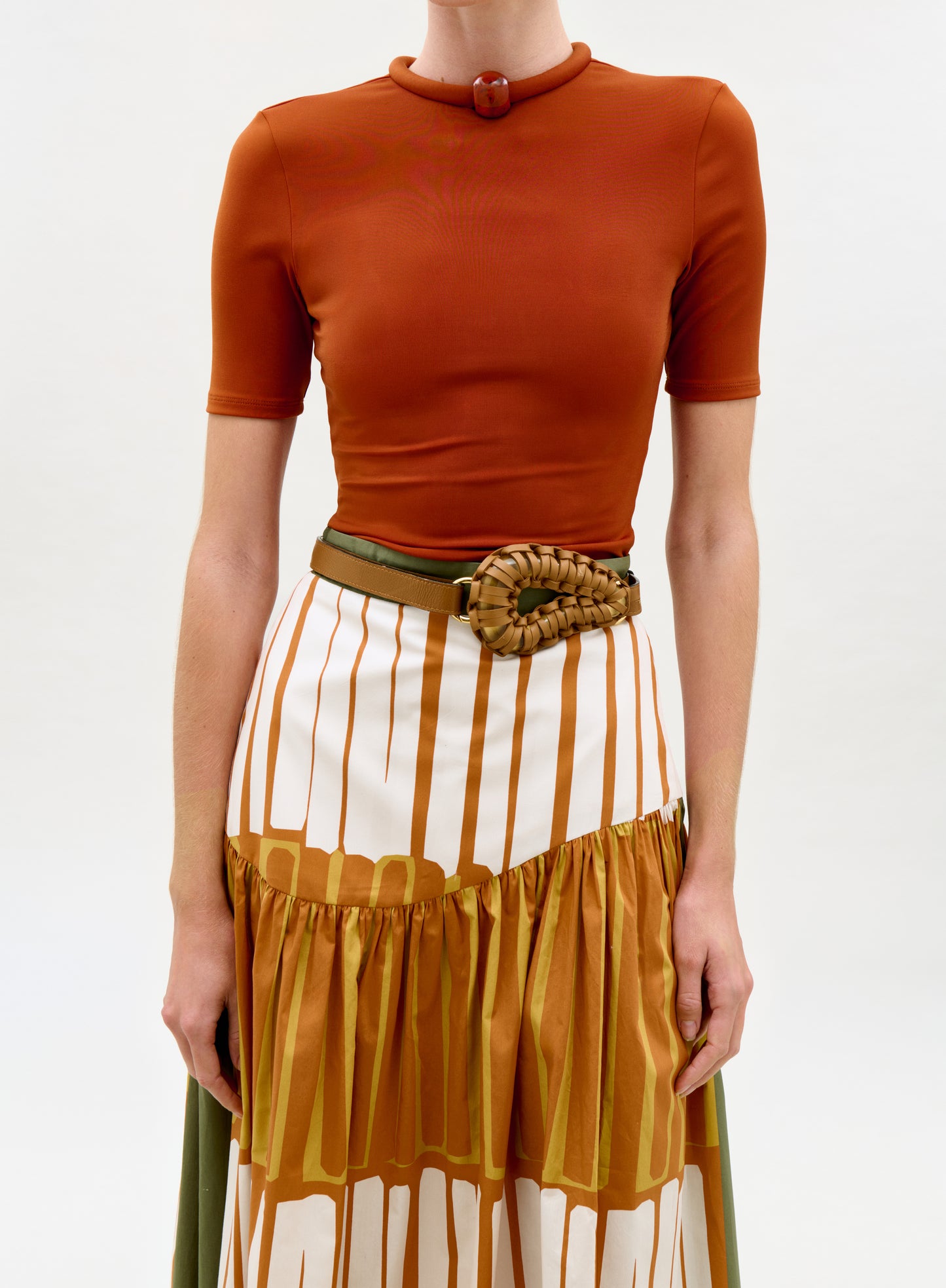 Person wearing an orange top and a multicolored skirt on a white background