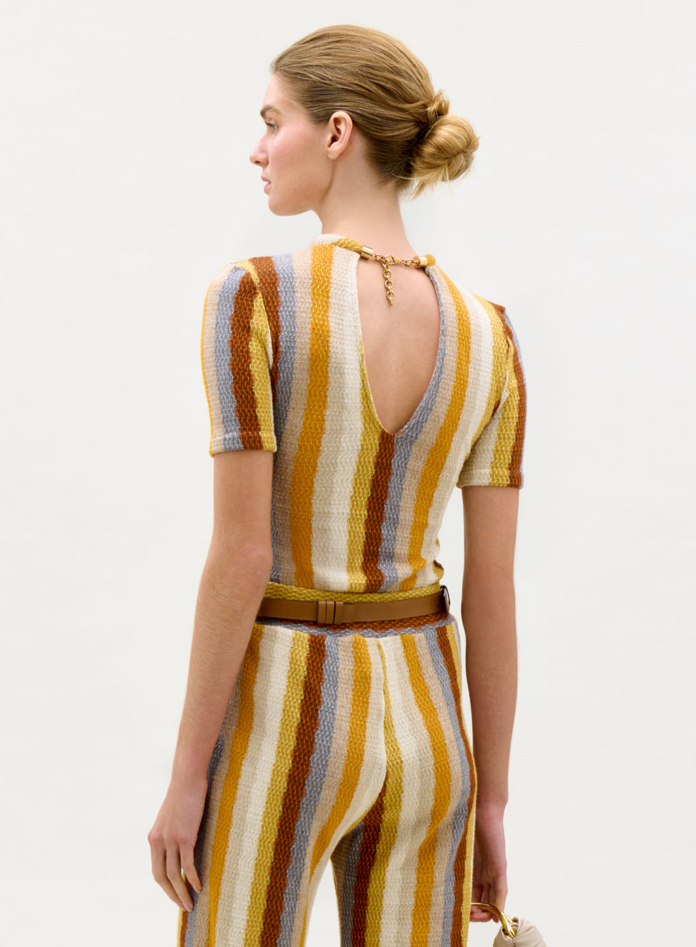 Woman wearing a striped outfit with a open back design on a white background