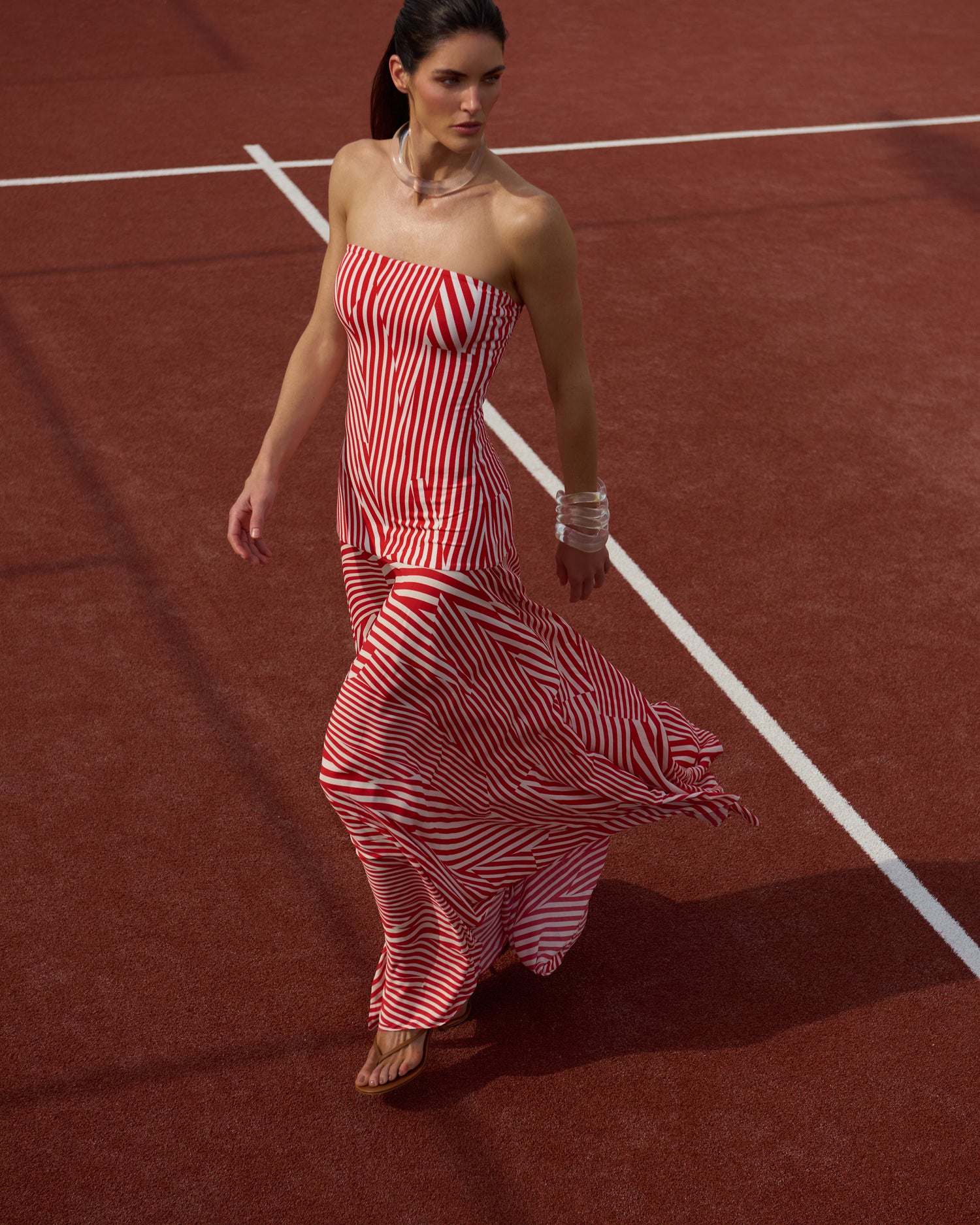 The Supermodel Hillary Rhoda in a red and white striped dress walking on a red surface.