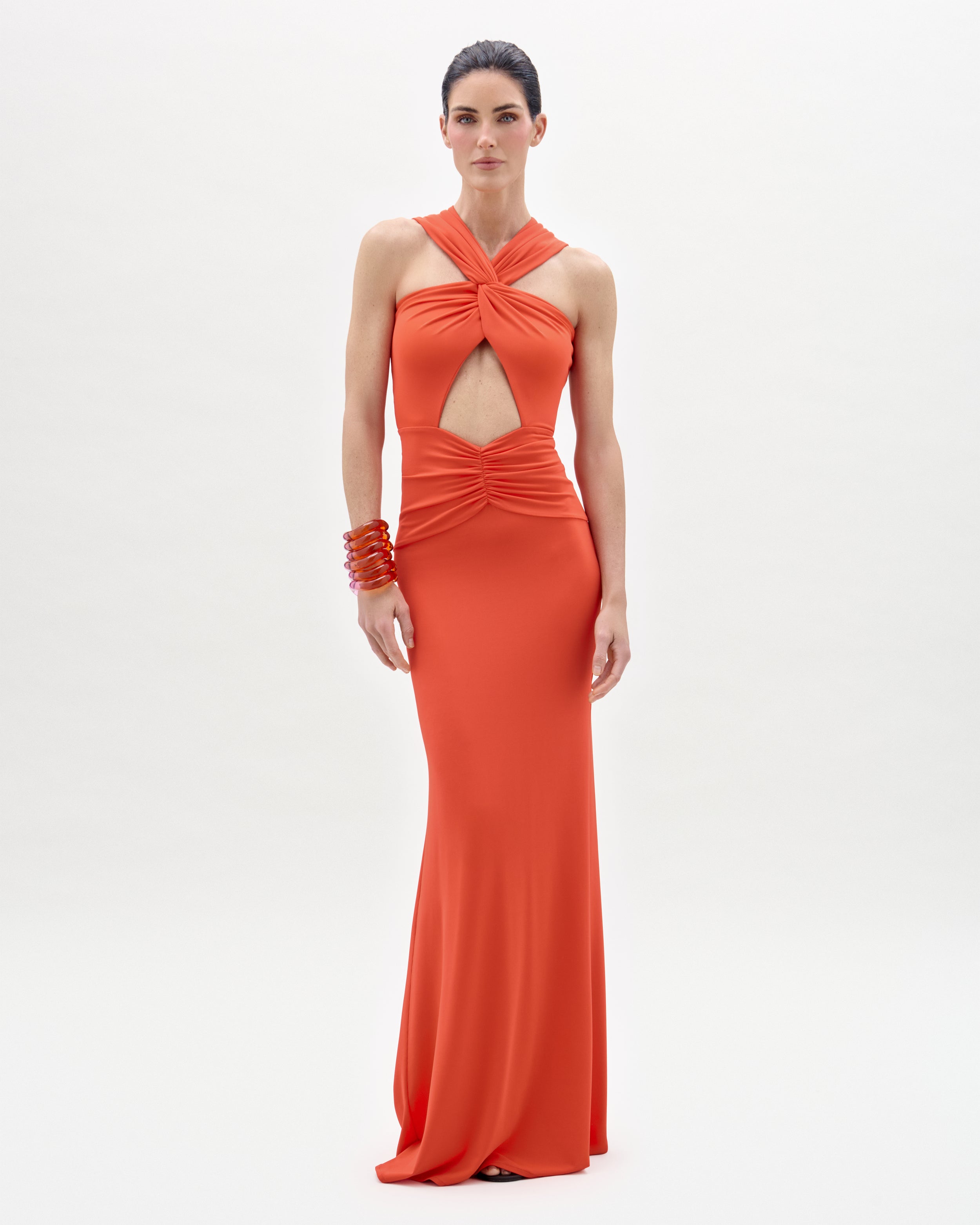Woman wearing an orange evening gown with a cutout design on a white background