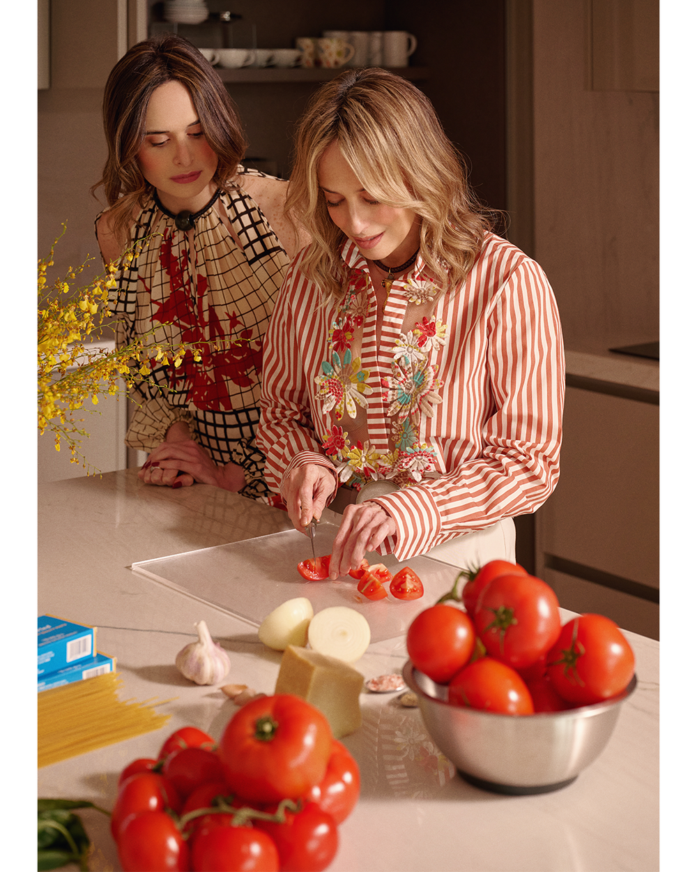 Two women preparing tomatoes in a kitchen.