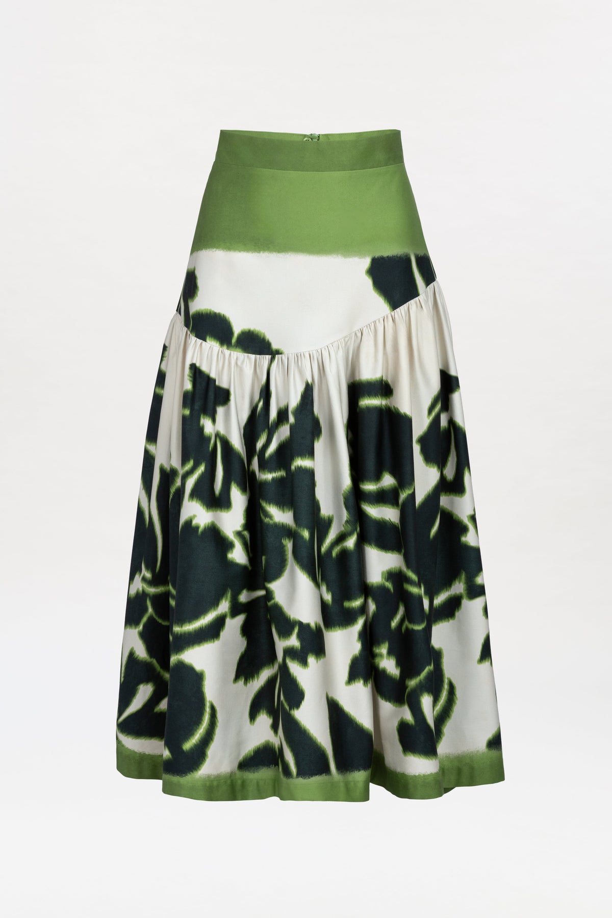 The Libby Skirt is a high-waisted, A-line skirt with a wide green waistband and hem, showcasing a white background adorned with large dark green floral patterns and subtle pleating.
