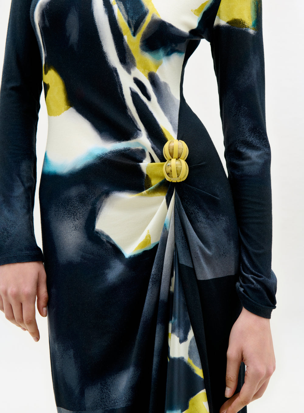 Black dress with abstract design and gold buttons on a white background