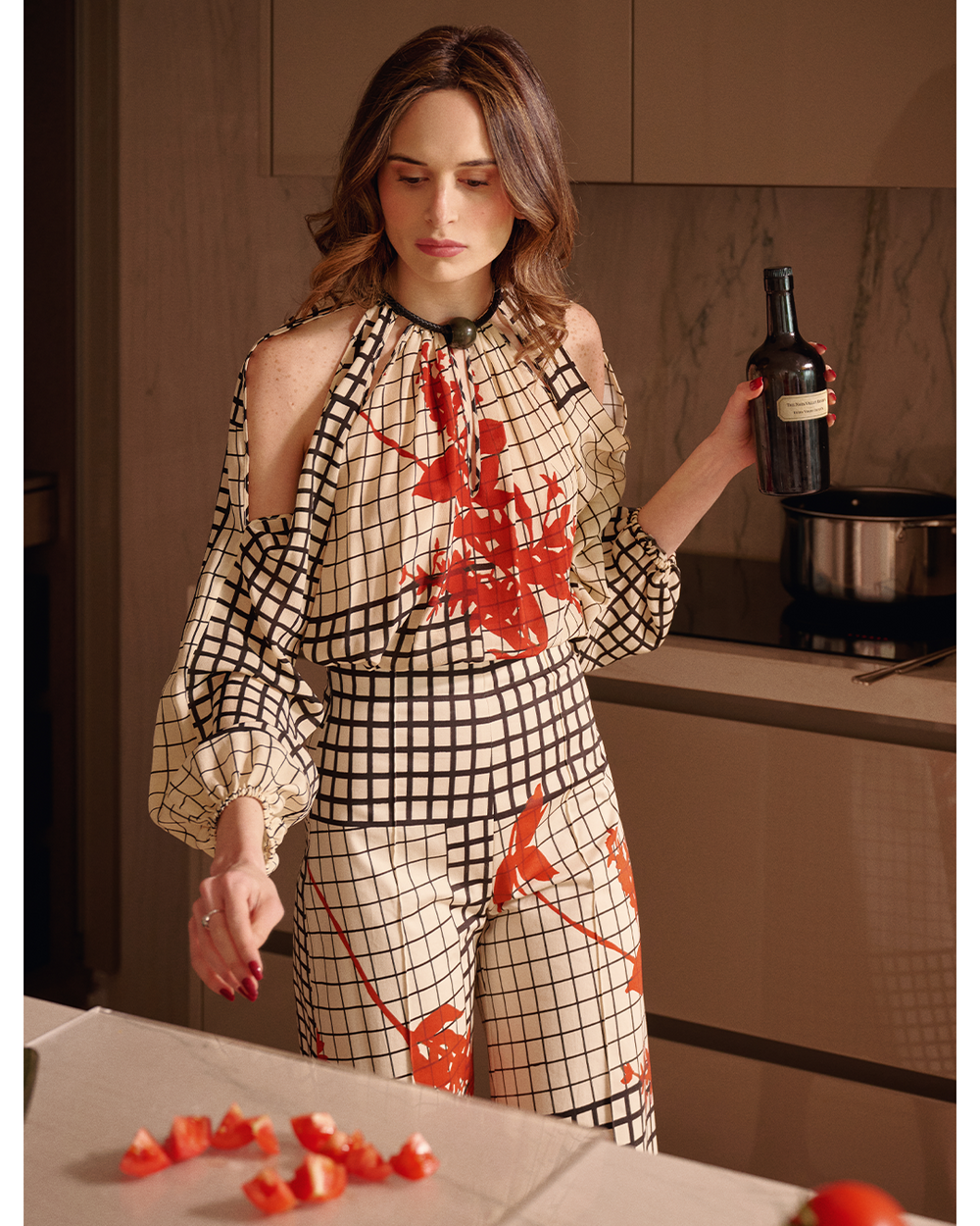 Woman in a stylish outfit with red floral patterns in a kitchen setting