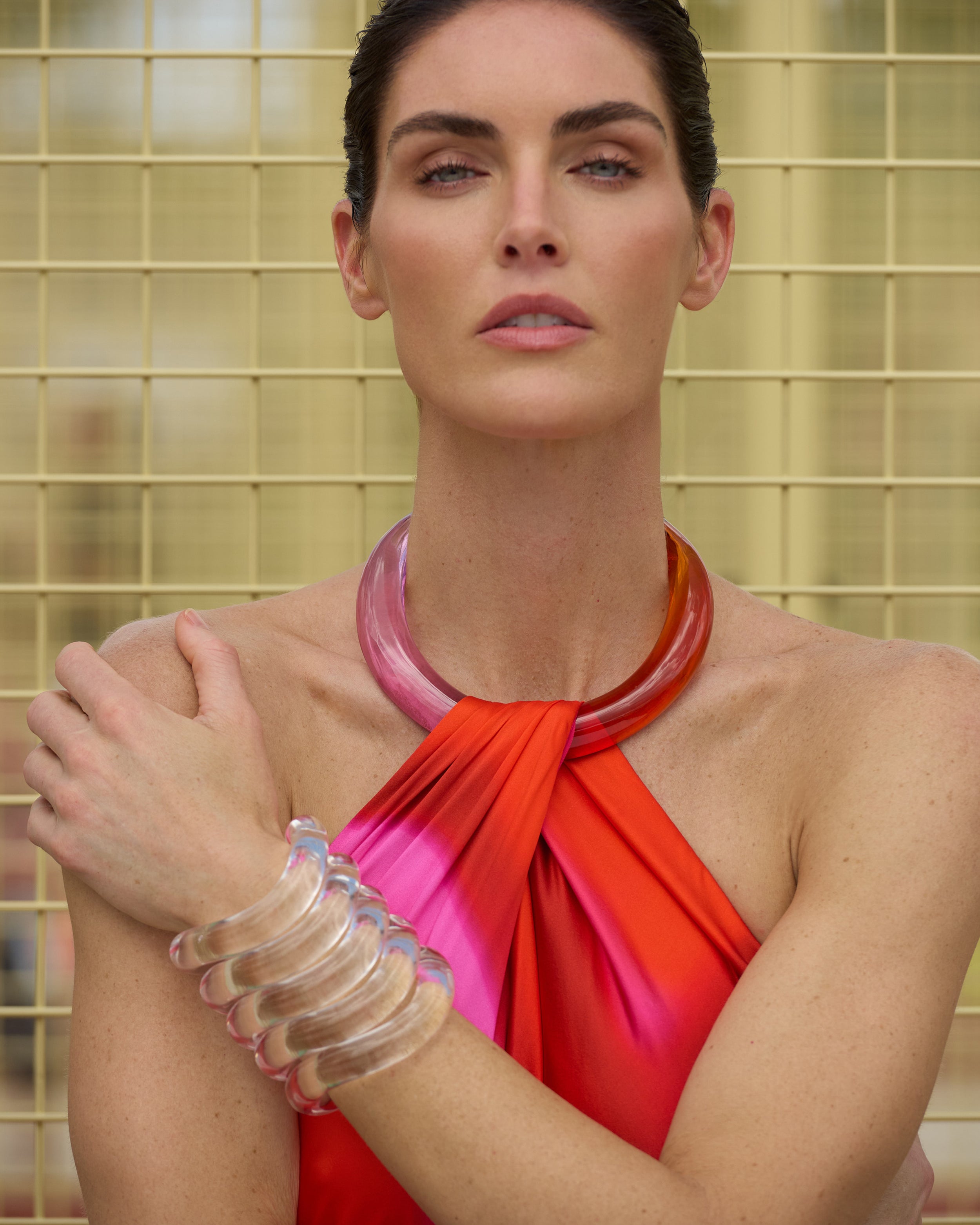 The supermodel Hillary Rhoda wearing a bright red top with a pink collar and multiple bracelets against a neutral background