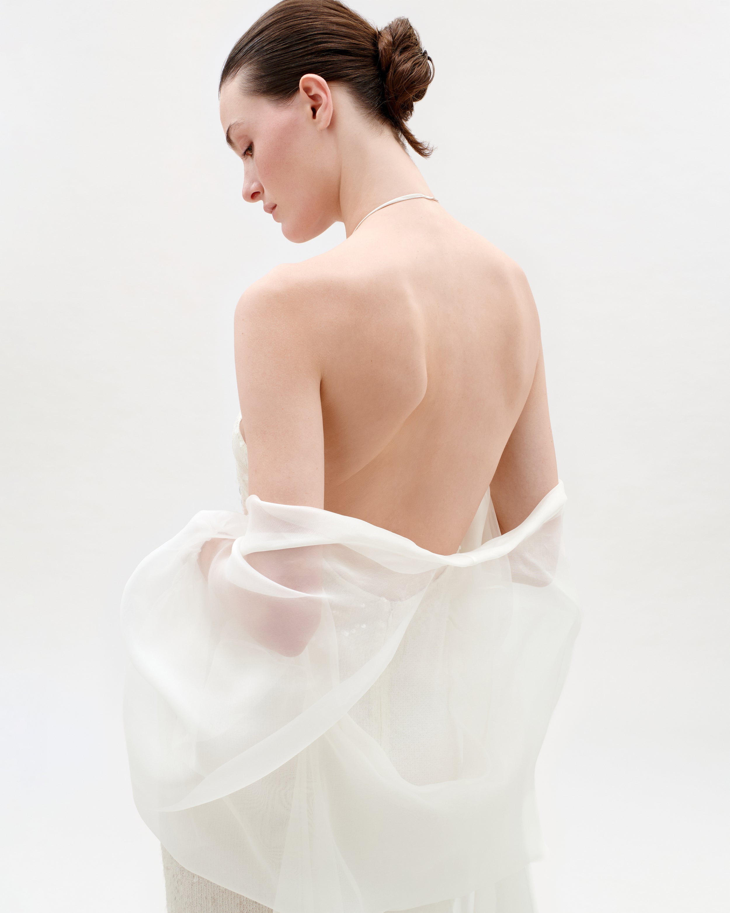 Woman wearing a sheer white garment against a light background
