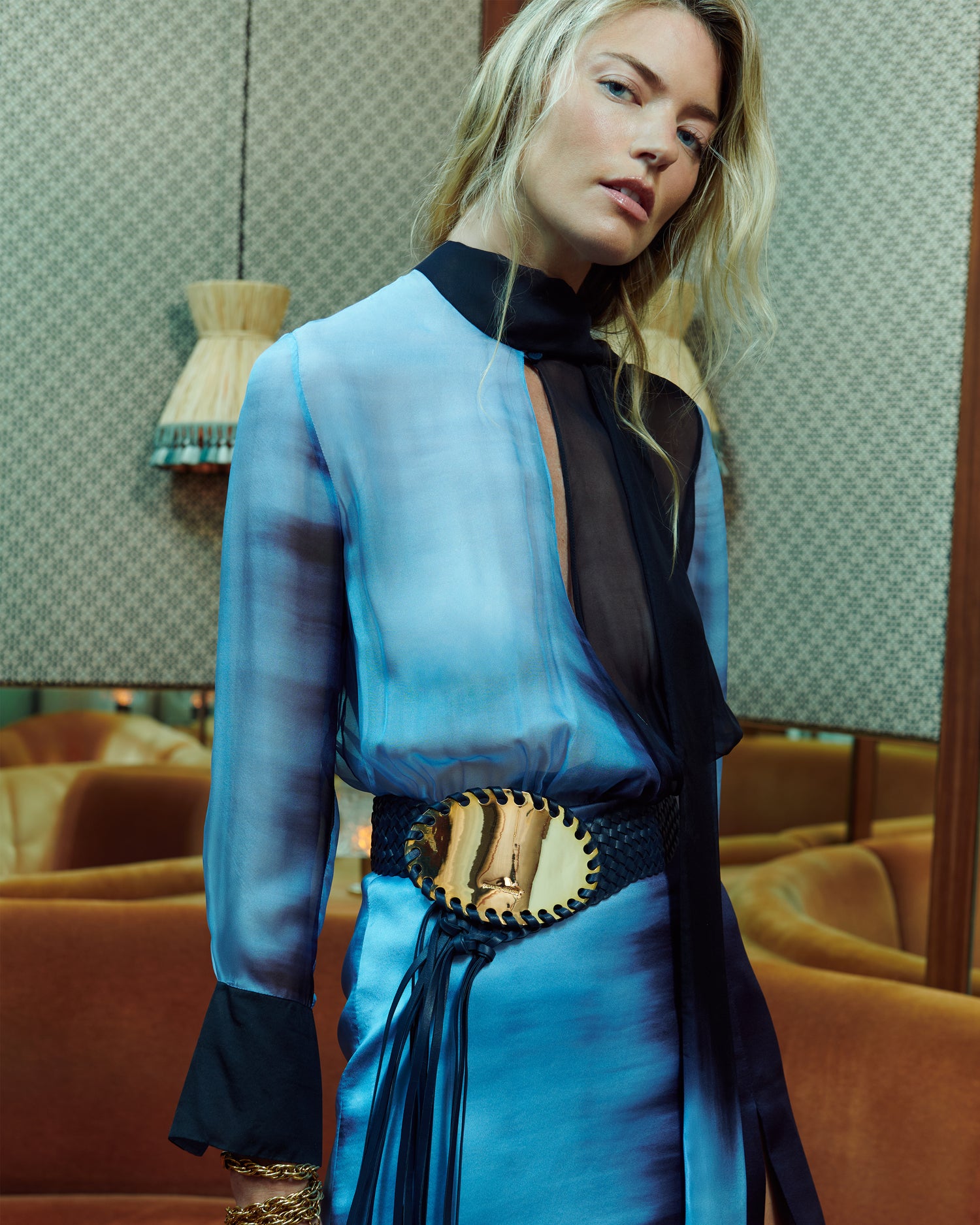 Woman wearing a blue dress with a gold belt in an indoor setting