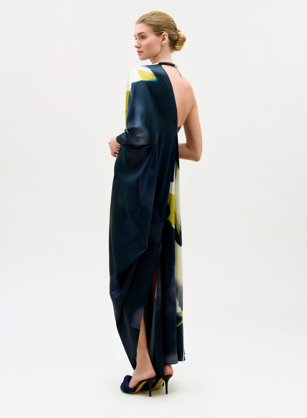 Woman wearing a long, dark blue dress with a white and yellow pattern on a white background
