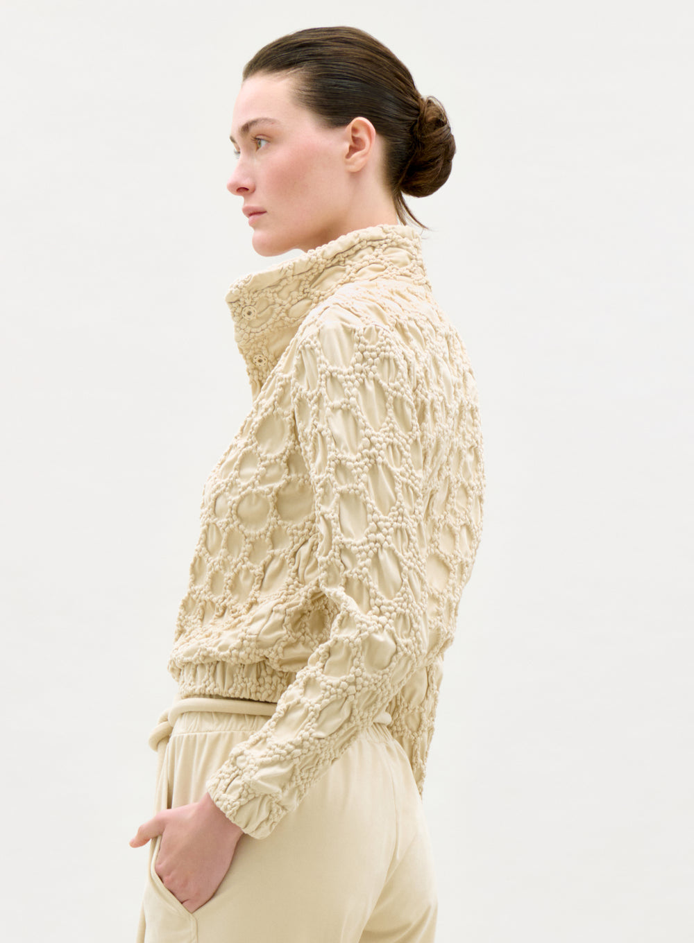 Woman wearing a textured beige jacket on a white background