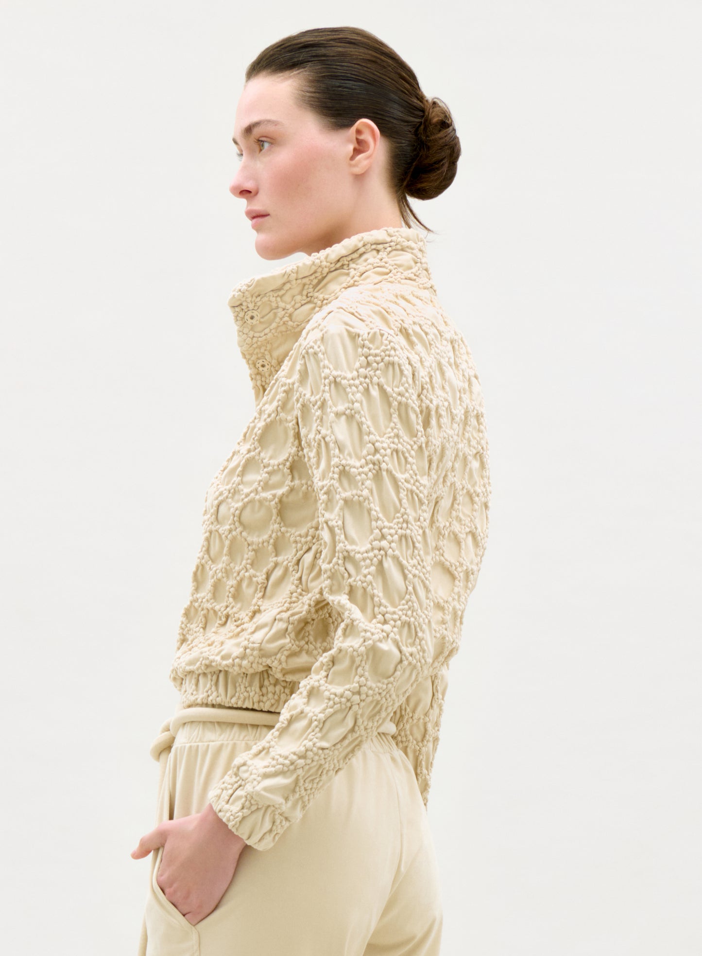 Woman wearing a textured beige jacket on a white background