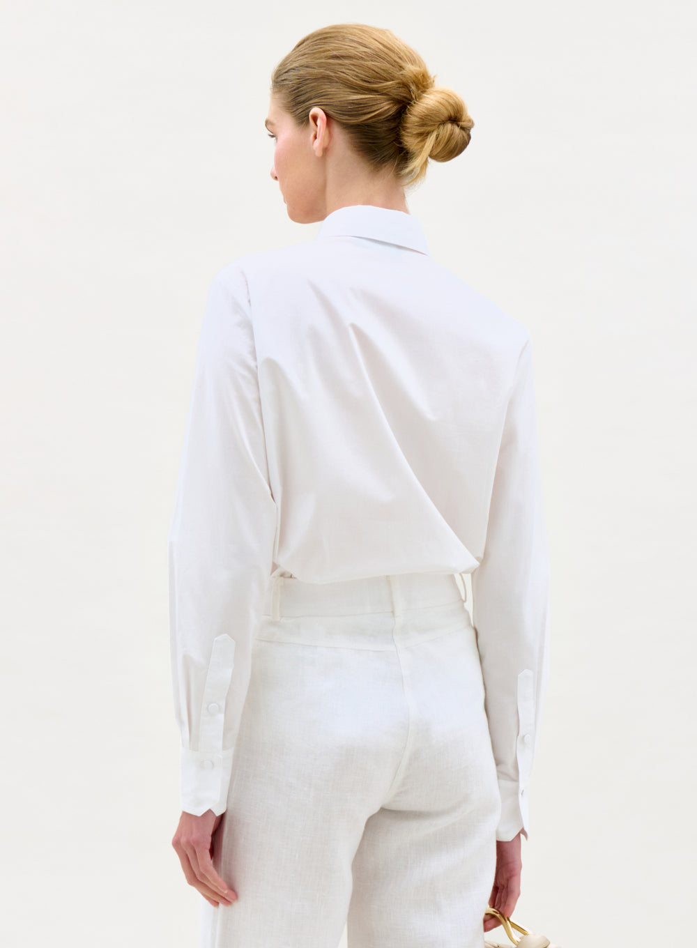 Woman wearing a white outfit against a plain background