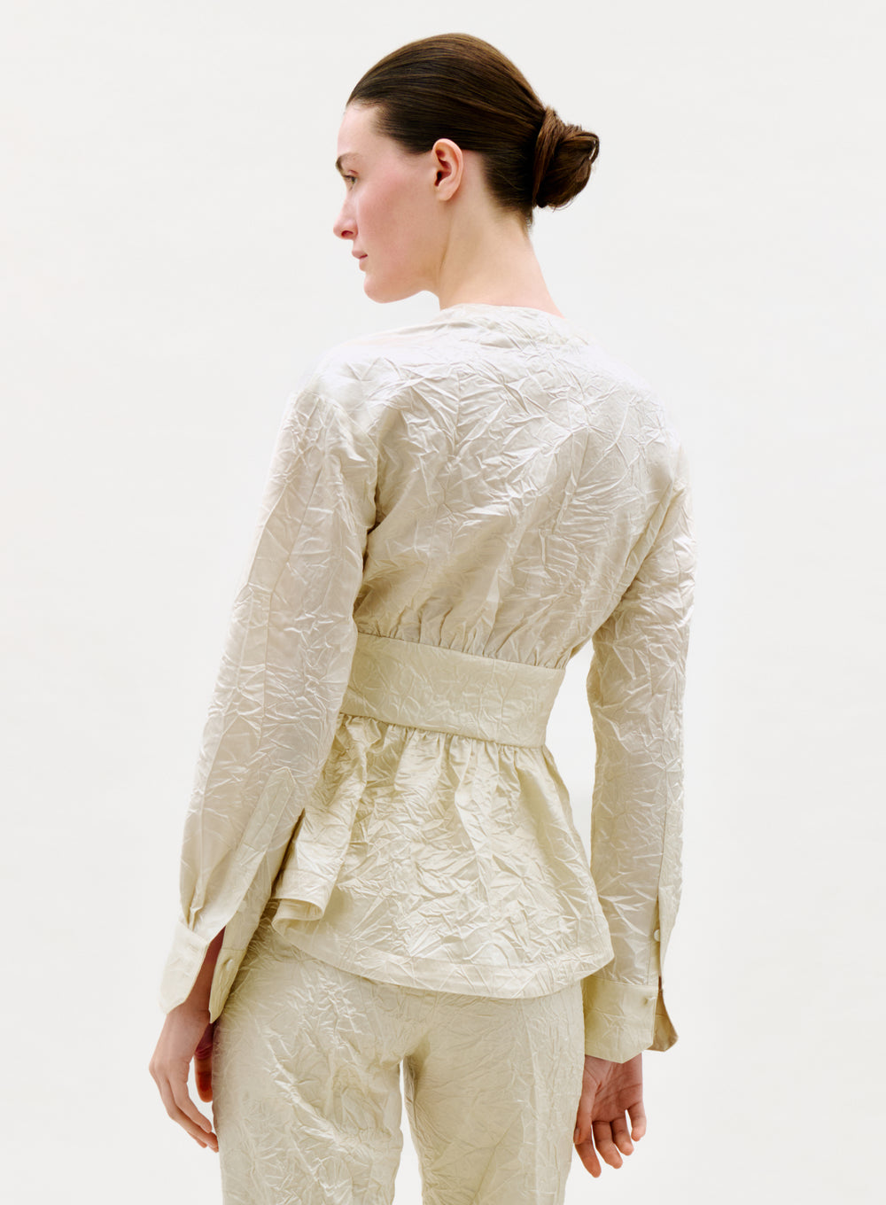 Woman wearing a cream-colored textured outfit on a white background