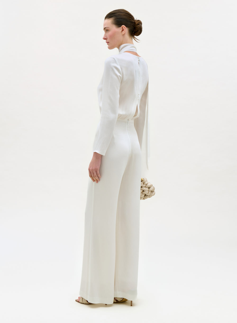 Woman wearing a white outfit with a high collar on a white background