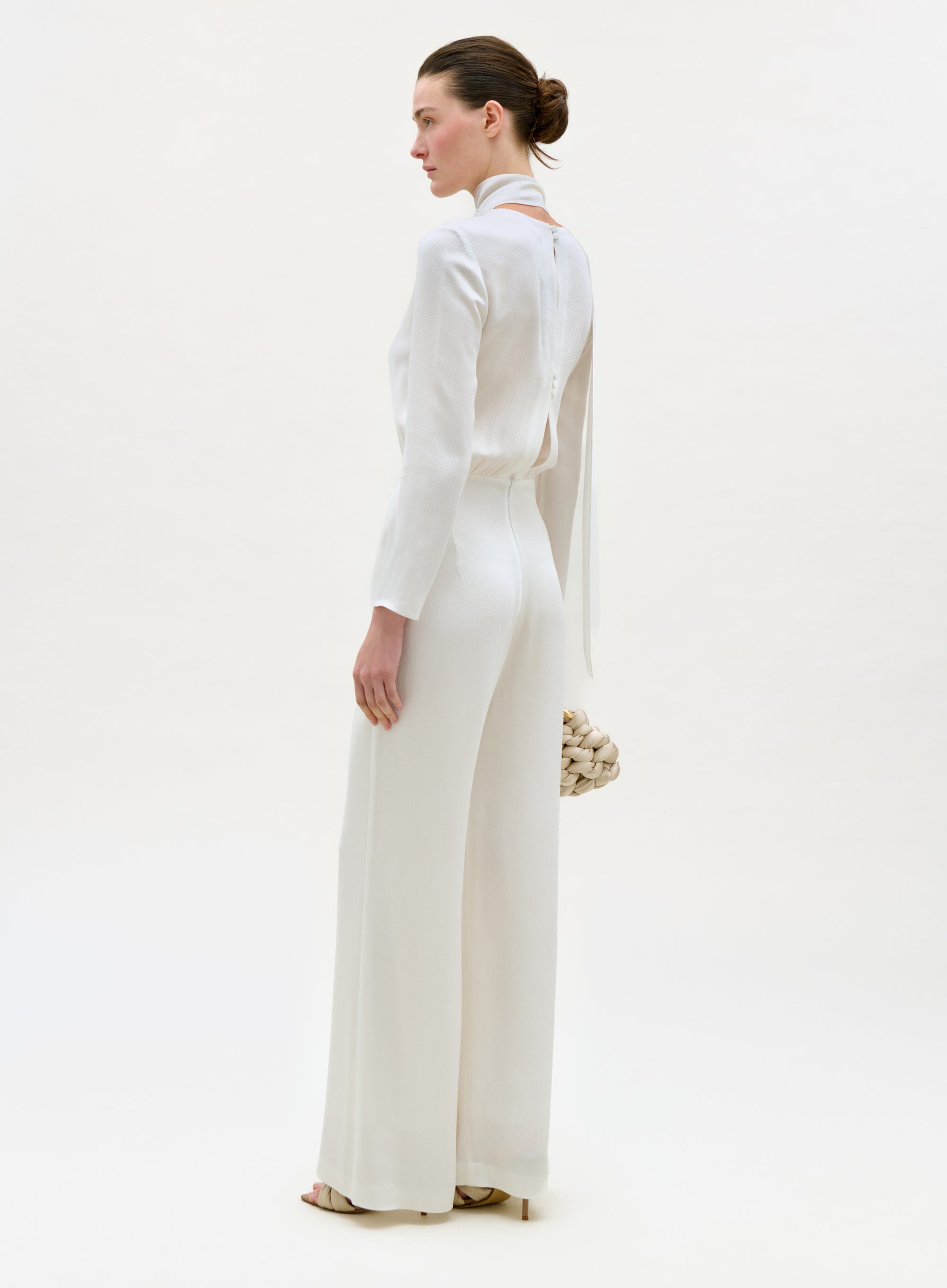 Woman wearing a white outfit with a high collar on a white background
