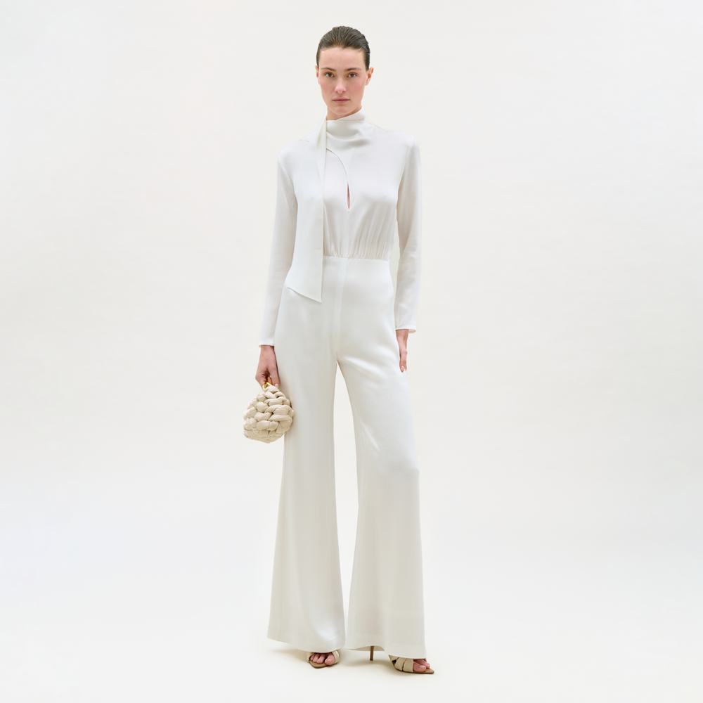 Woman in a white outfit holding a small bag on a white background
