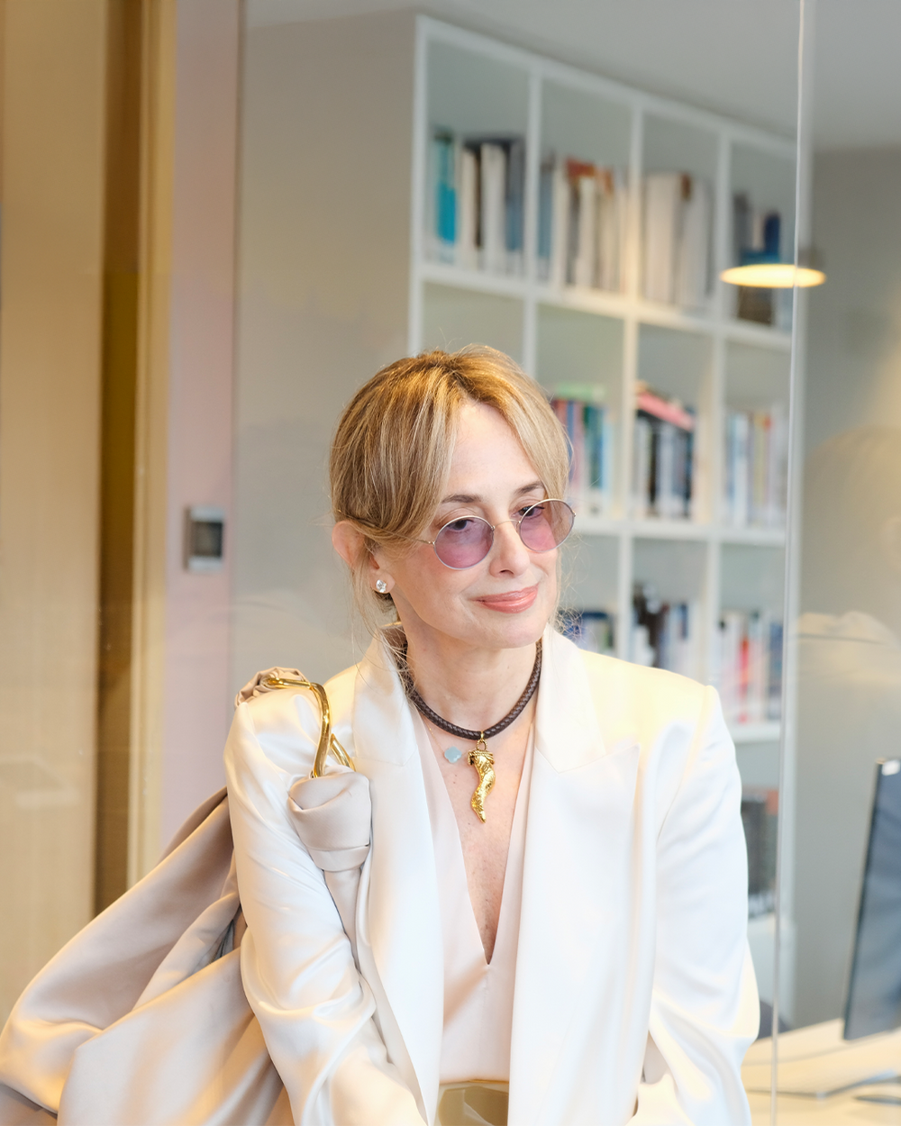 Person wearing a white blazer in an indoor setting with bookshelves in the background