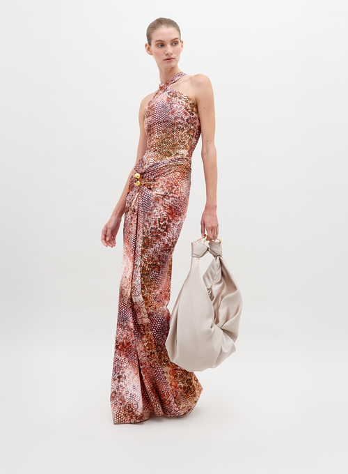 A person in a sleeveless, high-neck, colorful patterned Toyah Dress Peach Animal Print poses against a plain background, holding a large, light-colored slouchy bag. Available for pre-order now, with shipping scheduled by November 15th, 2024.