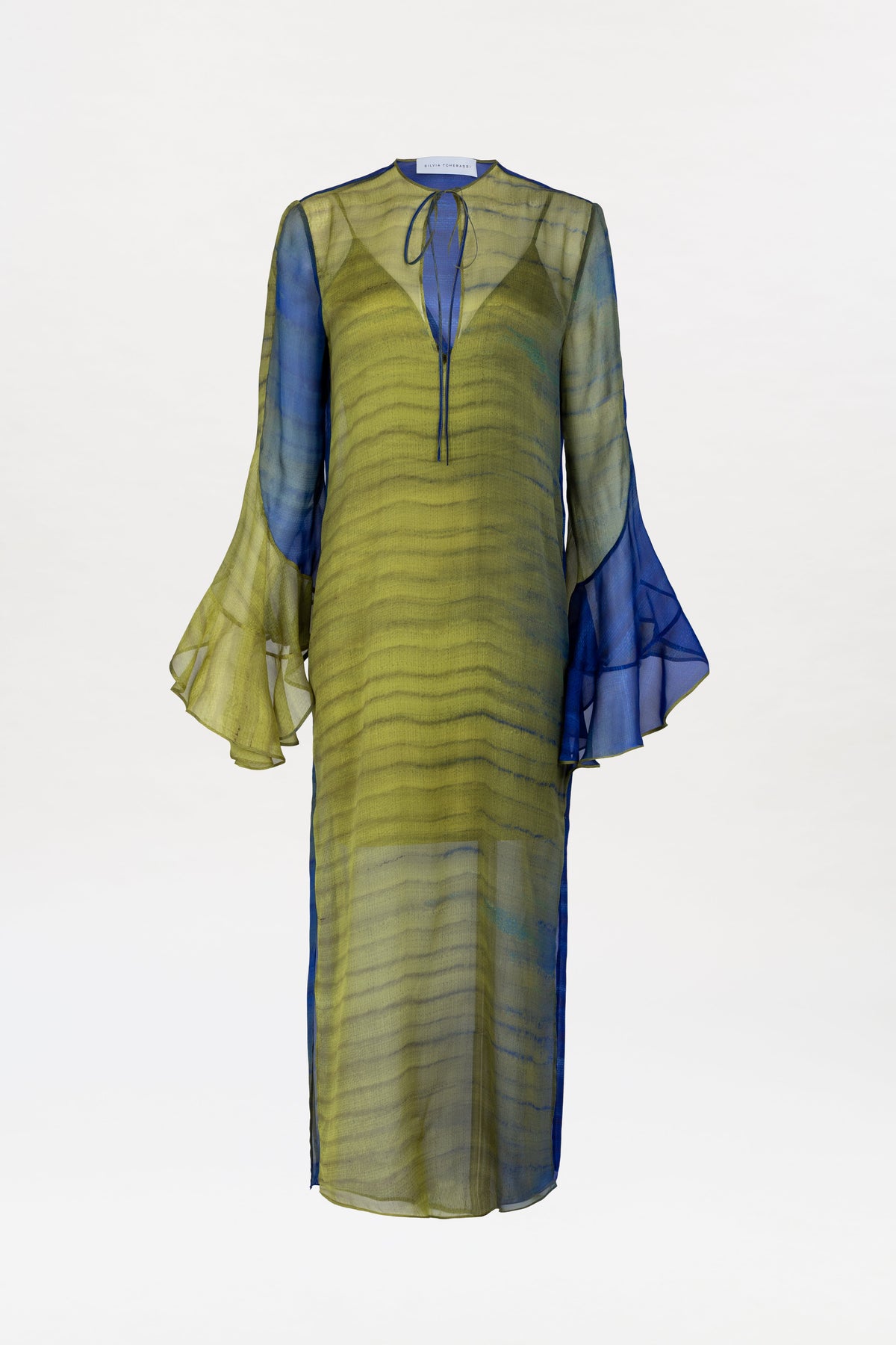 The Aries Dress is a lightweight, semi-transparent, long-sleeved dress featuring a green and blue ombre design, flared cuffs, a front tie at the neckline, and a mid-calf length.