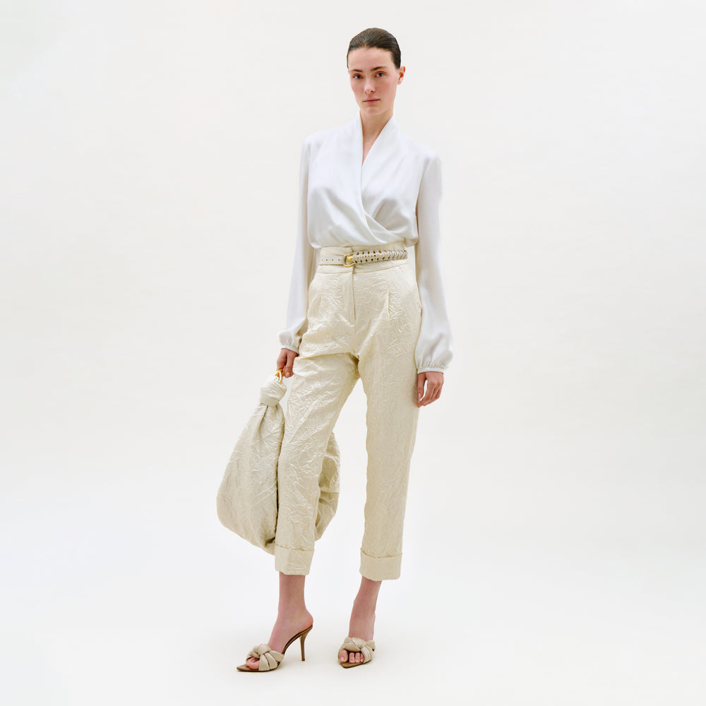 Woman wearing a white blouse and beige pants on a white background