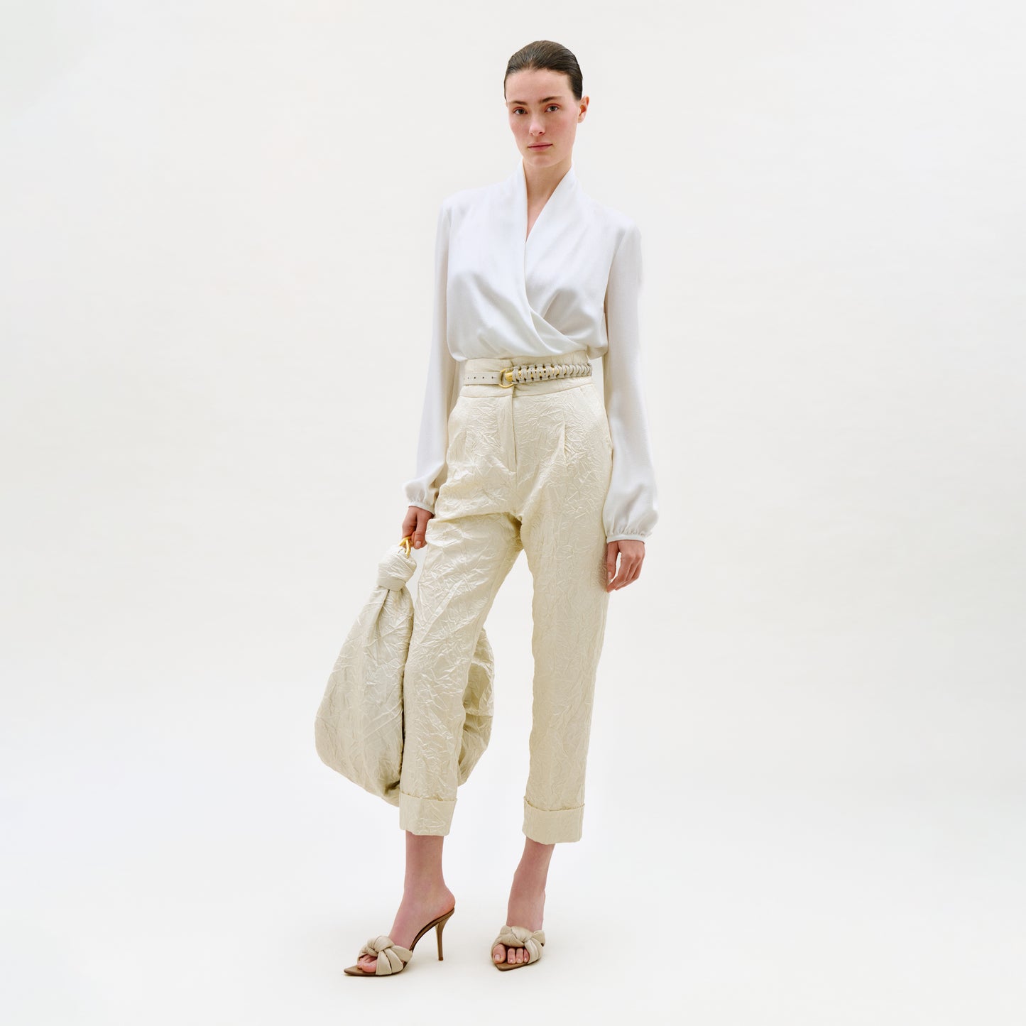 Woman wearing a white blouse and beige pants on a white background