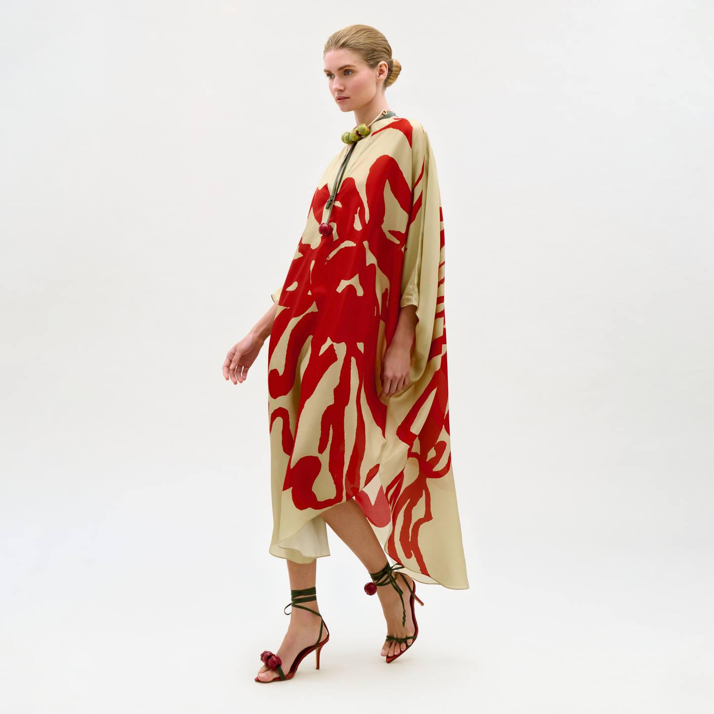 Woman wearing a red and beige patterned dress on a white background