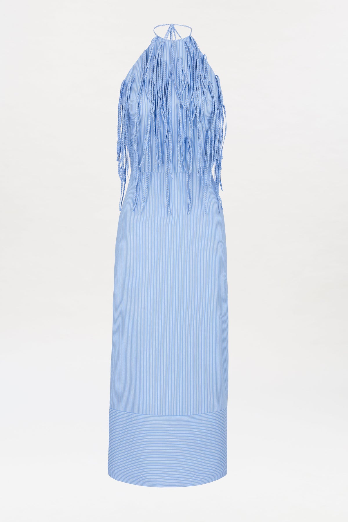 The Otilia Dress is a light blue, sleeveless, ankle-length dress with a halter neckline. It features long, thin fringe details that dangle from the top and is made from a lightweight, slightly textured fabric with a straight silhouette.