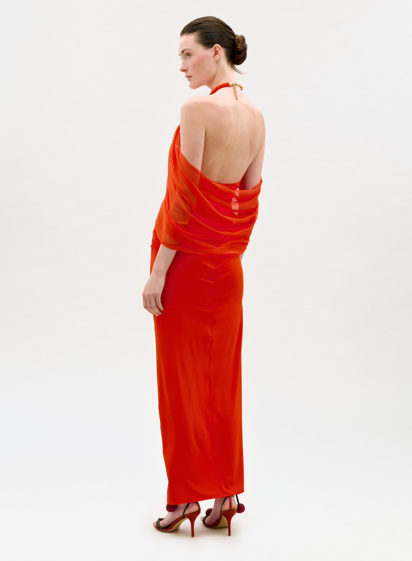 Woman wearing a bright orange evening gown on a white background